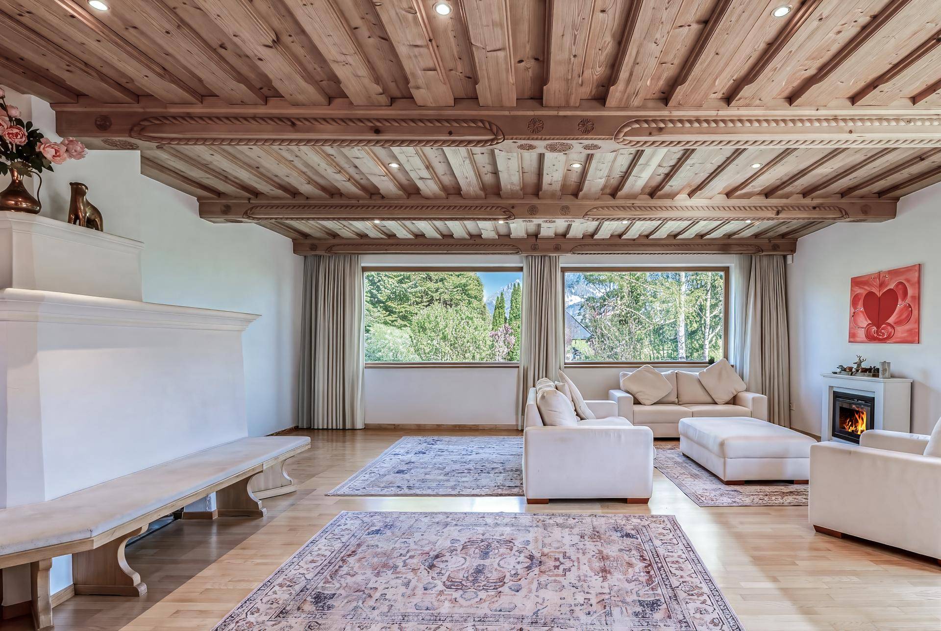 Geräumiges Wohnzimmer mit Holzbalkendecke, hellem Parkettboden und gemütlichem Kamin.