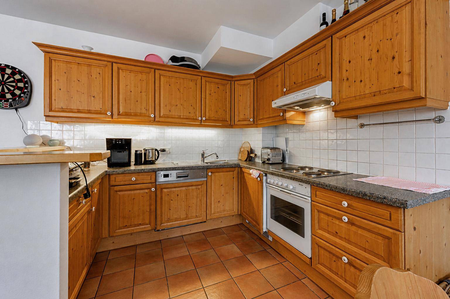 Detailansicht der Holzküche mit Granitarbeitsplatte und integrierten Geräten.