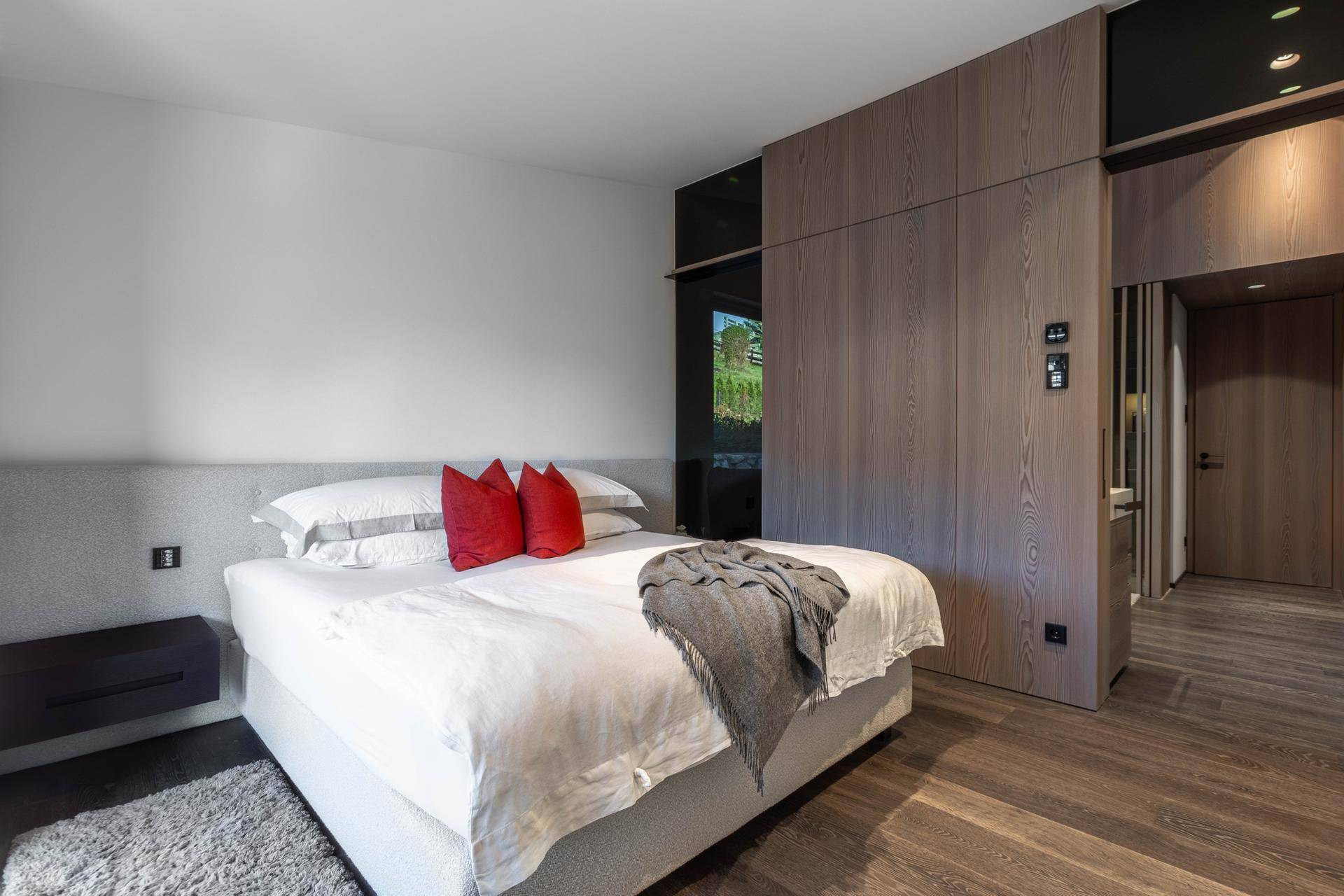 Modernes Schlafzimmer mit integrierten Holzschränken, komfortablem Bett und dunklem Holzboden.