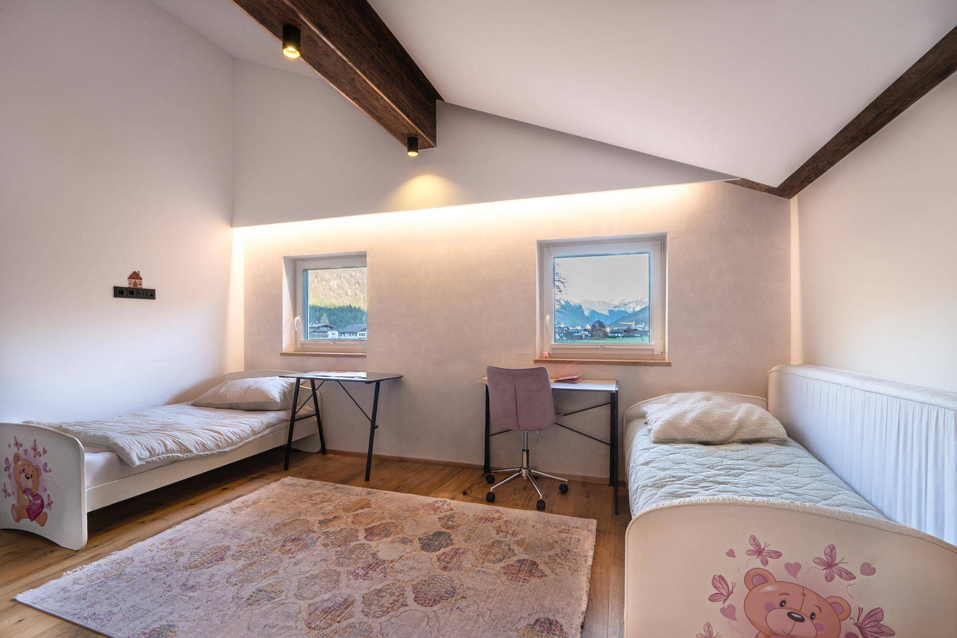 Kinderzimmer mit zwei Betten, Schreibtischen und Blick auf die Berge.