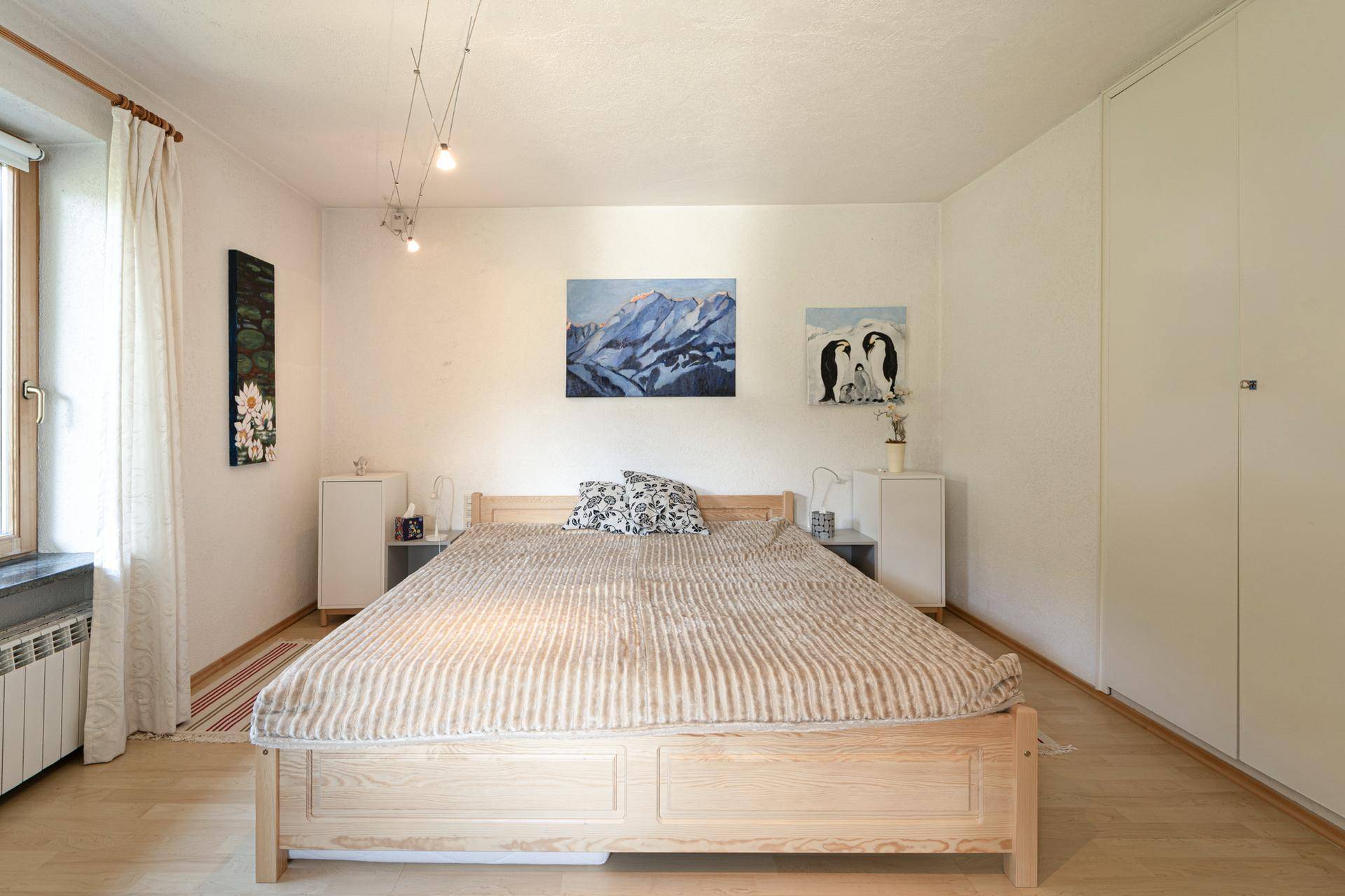 Schlafzimmer mit Holzbett, Einbauschränken und einem Fenster mit Blick nach draußen.