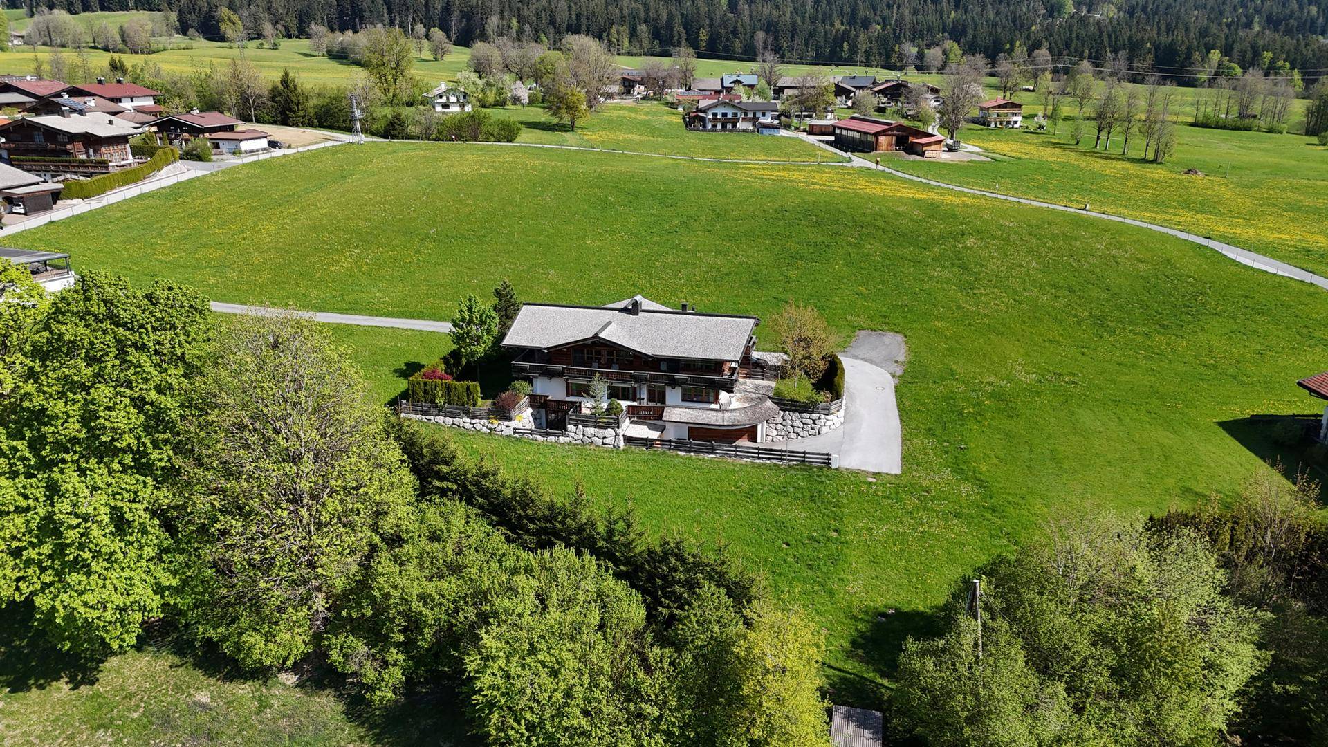 Panoramablick auf das Anwesen, eingebettet in eine weitläufige grüne Hügellandschaft mit Bäumen.