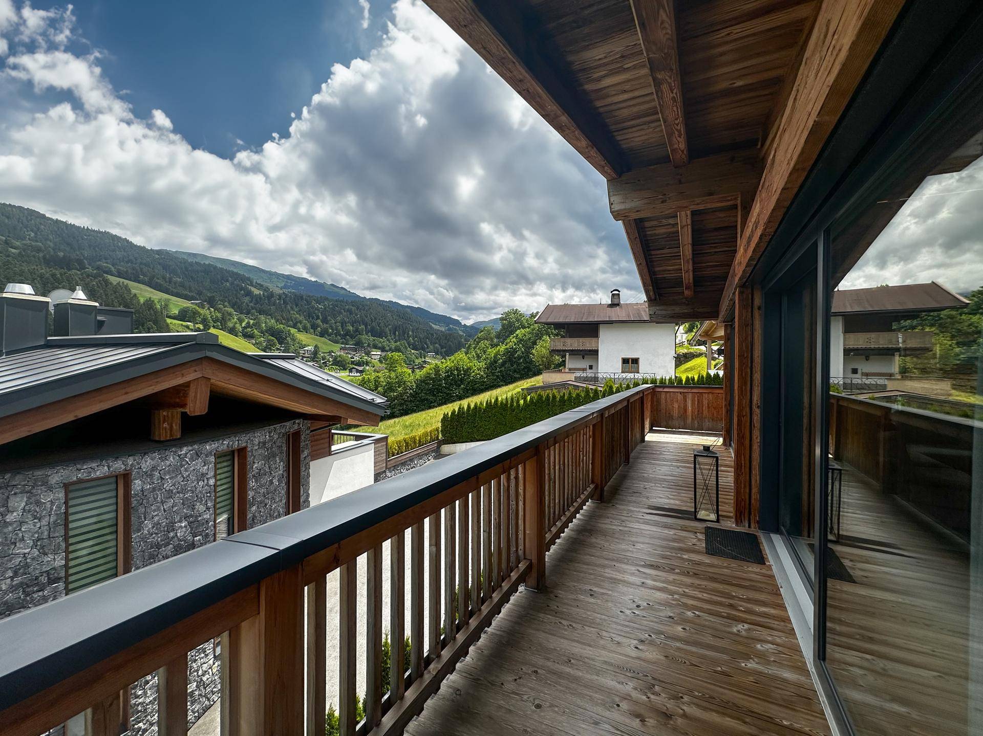 Langer Holzbalkon mit Bergblick und traditionellem Geländer, ideal zum Entspannen im Freien.
