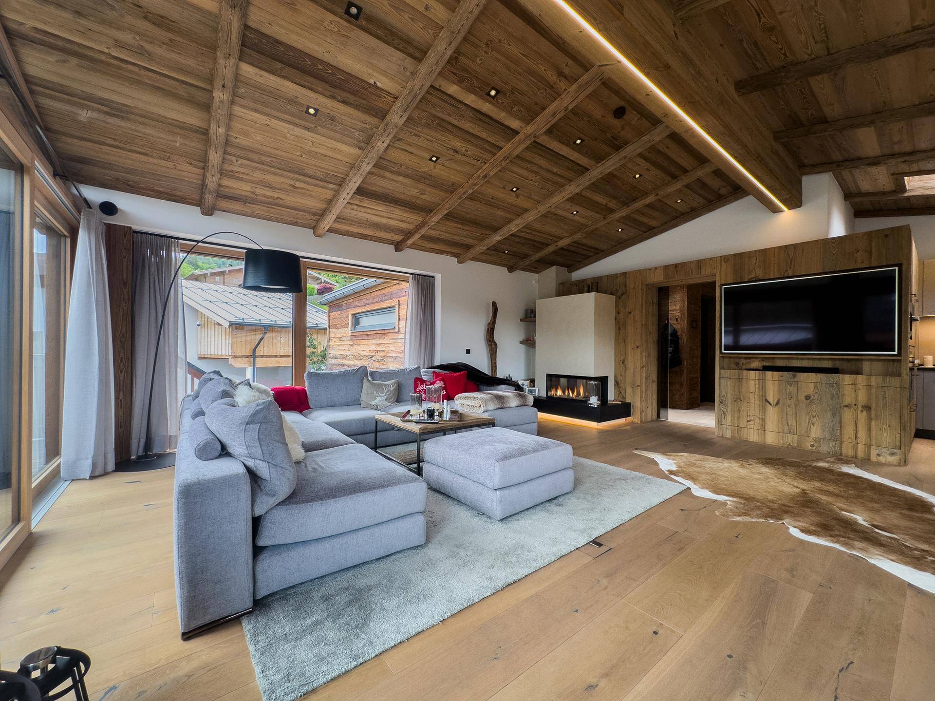 Gemütlicher Wohnbereich mit großem Sofa, Kamin und Zugang zu einer Terrasse oder Balkon.