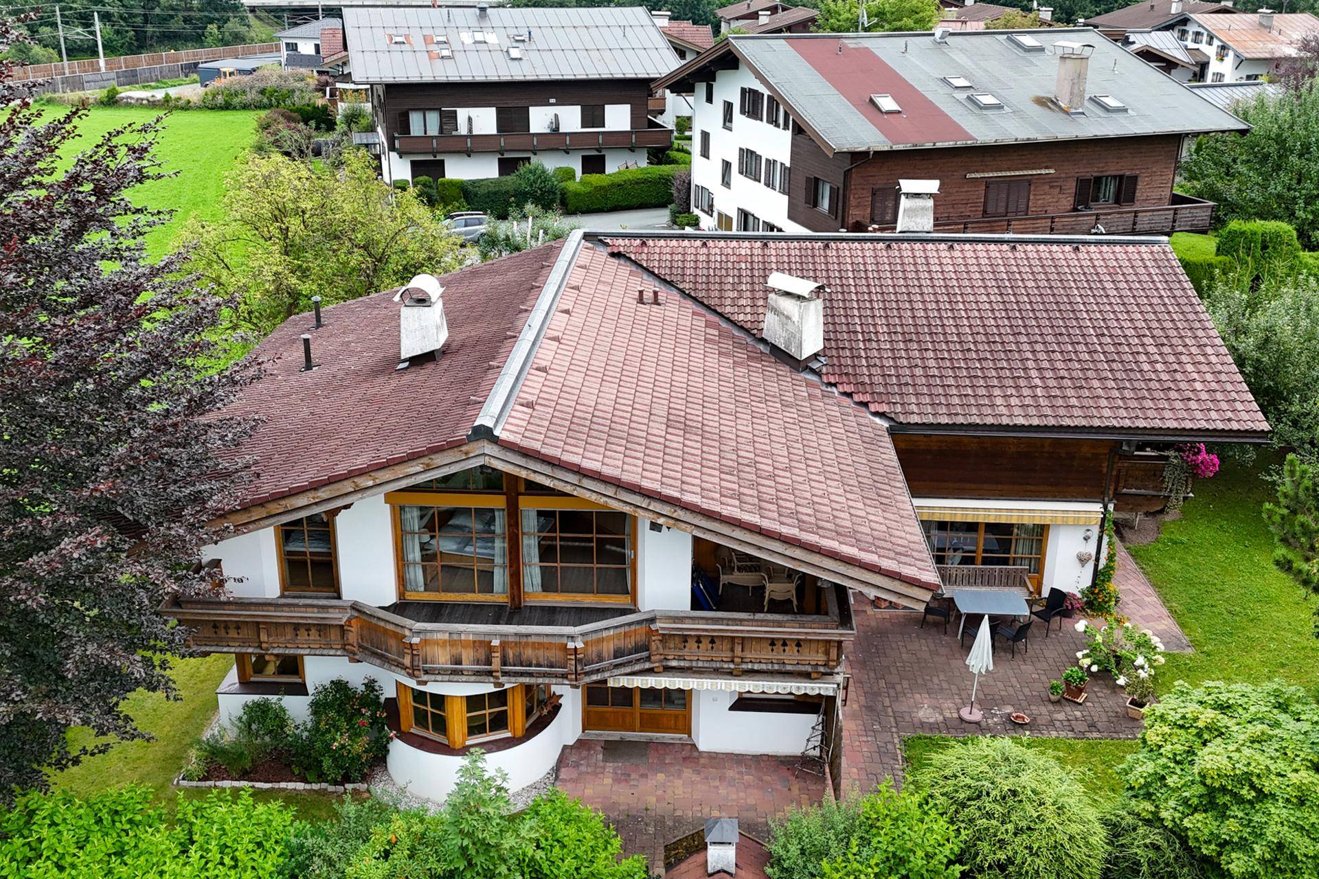 Luftaufnahme eines gepflegten Hauses mit mehreren Balkonen und einer einladenden Terrasse.
