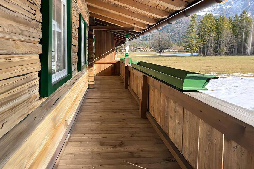 Heller Holzbalkon mit Blick auf die umliegende Berglandschaft und Wiesen.