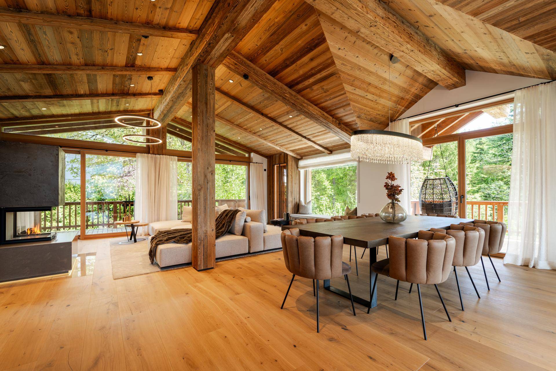 Eleganter Wohn-Essbereich mit modernem Kamin, bequemer Sofalandschaft und luxuriösem Kronleuchter.
