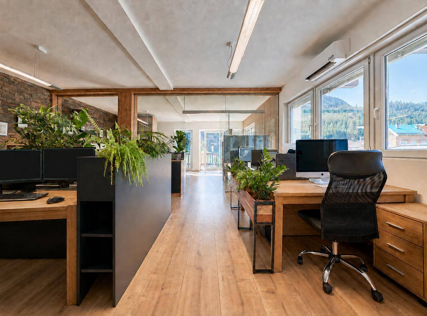 Helles Büro mit großen Fenstern, Holzboden und Blick auf die umliegende Berglandschaft.