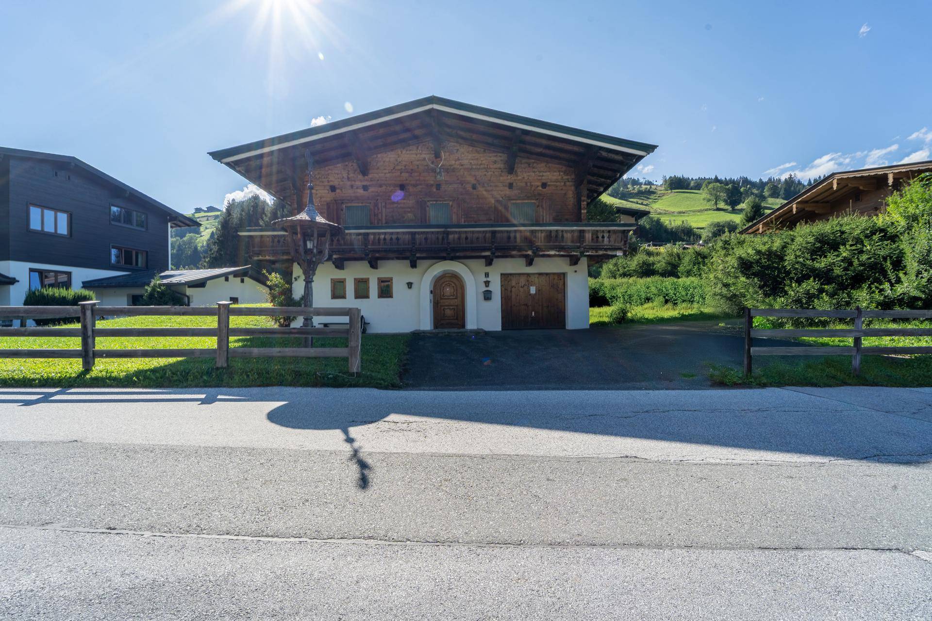 Traditionelles Einfamilienhaus im alpenländischen Stil mit Holzbalkon und gepflegter Zufahrt.