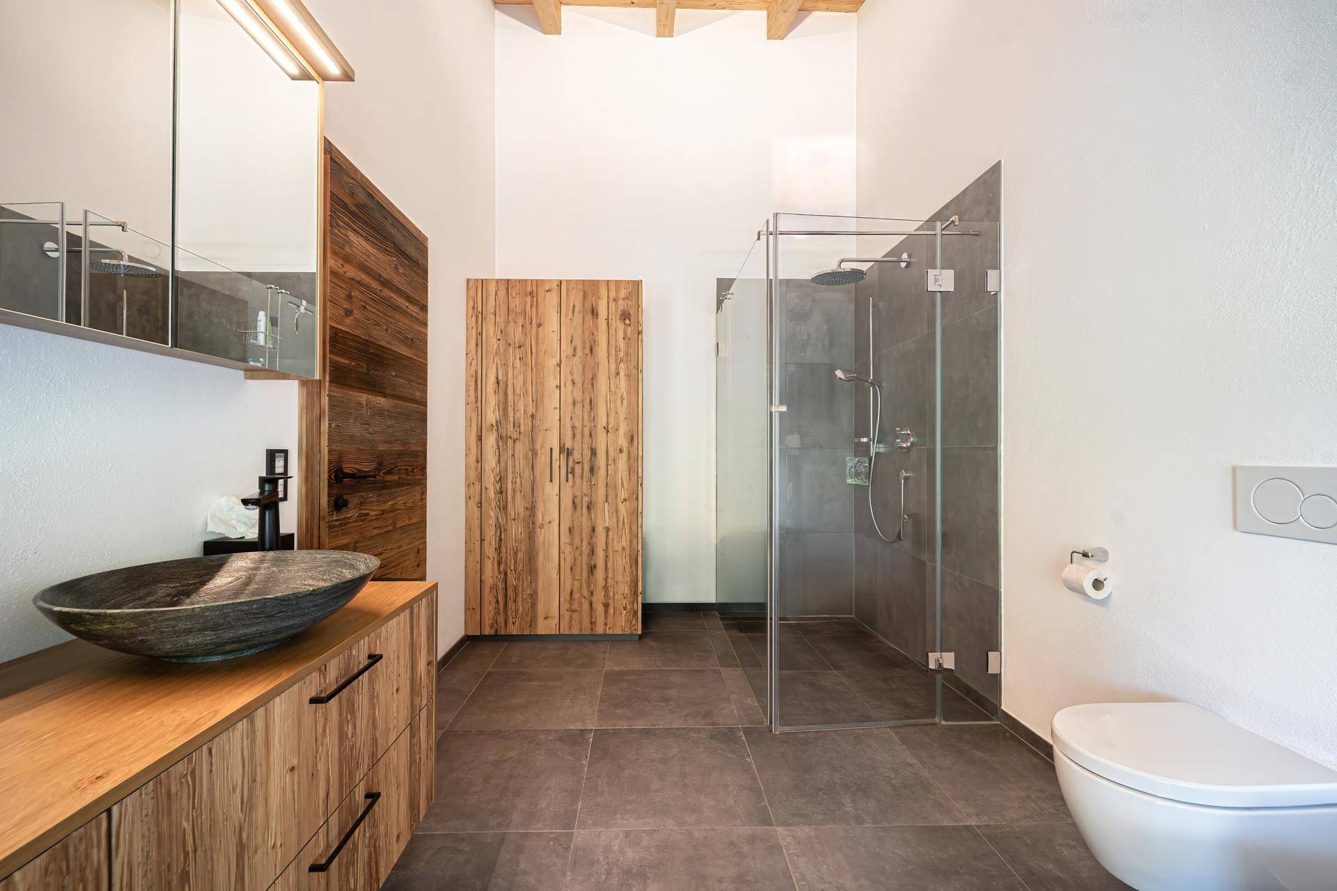 Elegantes Badezimmer mit begehbarer Dusche, Einzelwaschbecken und modernen Fliesen.