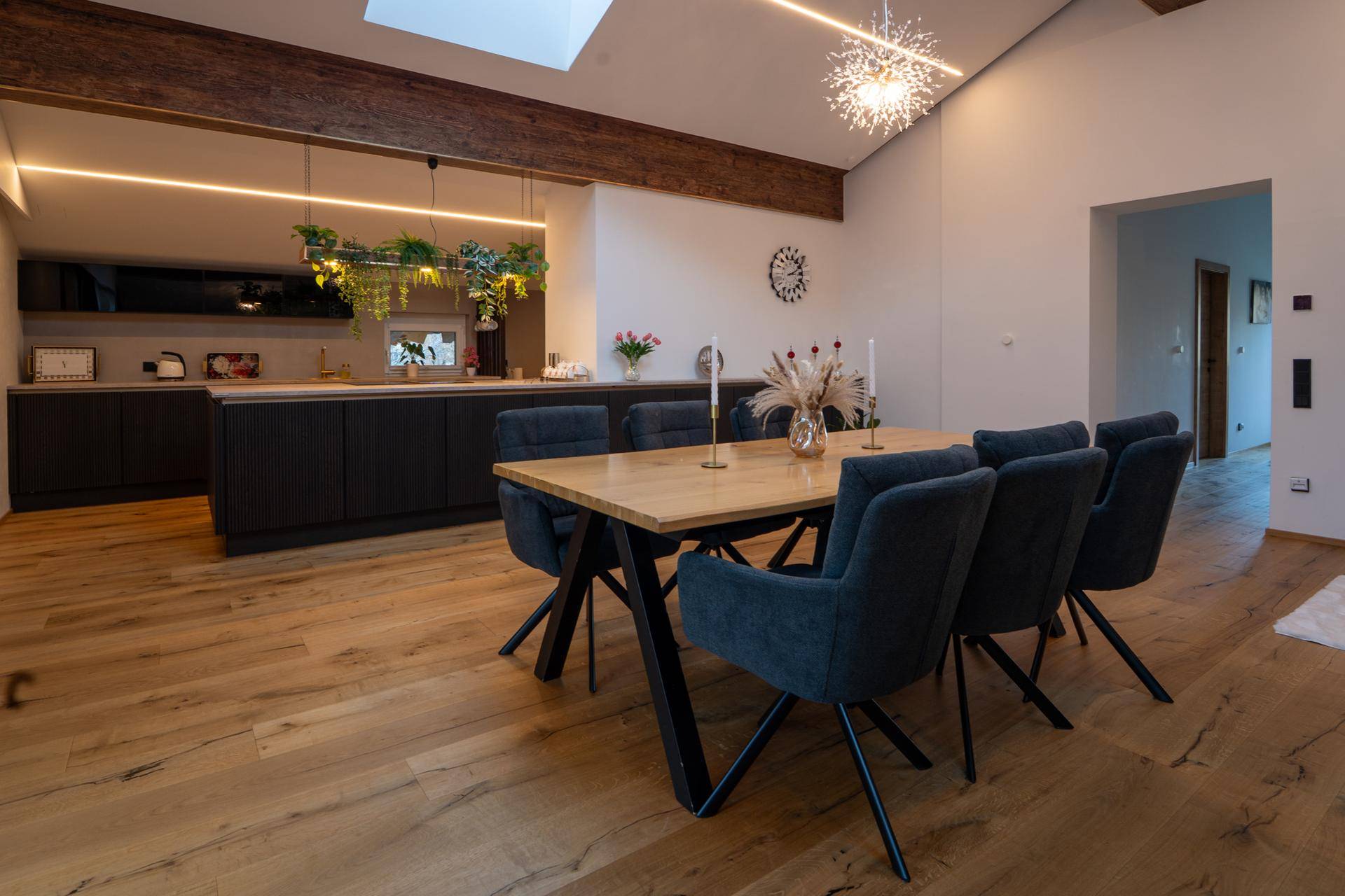 Heller Essbereich mit Holztisch und Blick auf die offene, moderne Küche.
