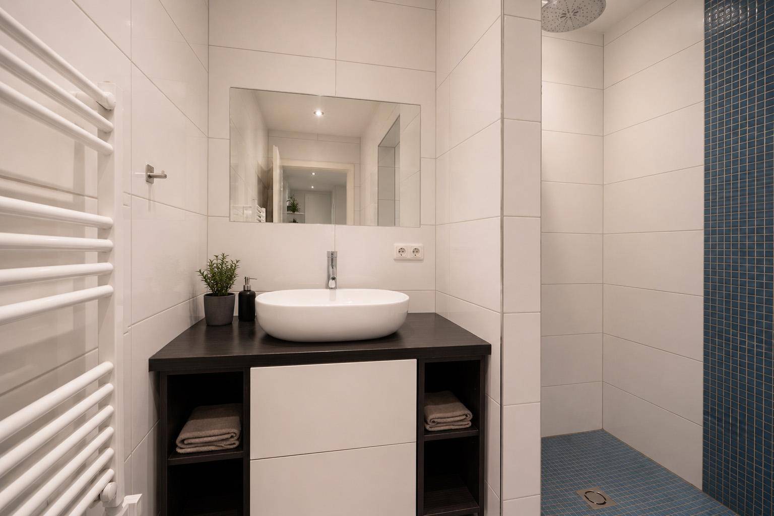 Modernes Badezimmer mit Aufsatzwaschbecken, beheiztem Handtuchhalter und Duschbereich.