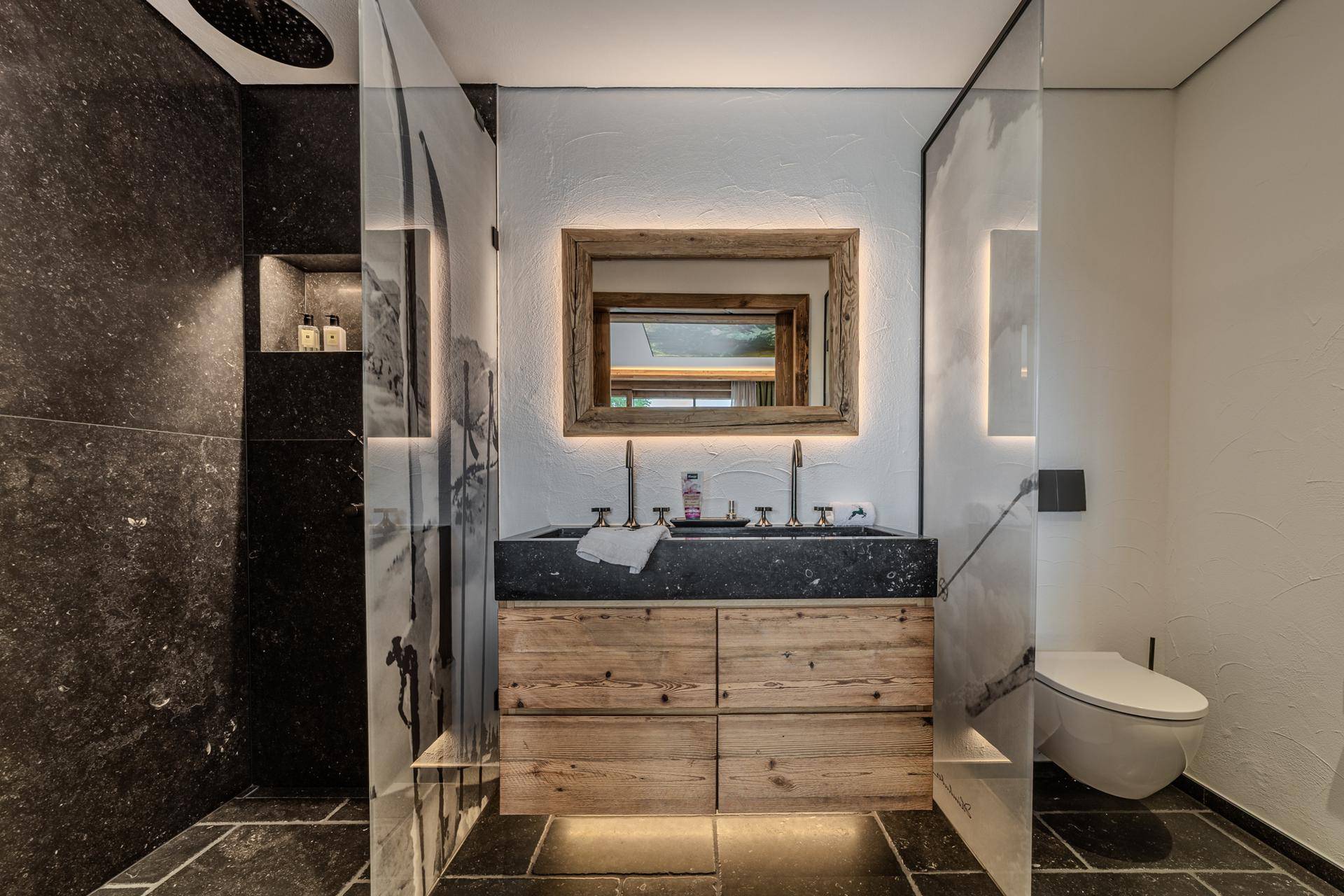 Elegantes Badezimmer mit Doppelwaschbecken aus Stein, begehbarer Dusche und Wand-WC.
