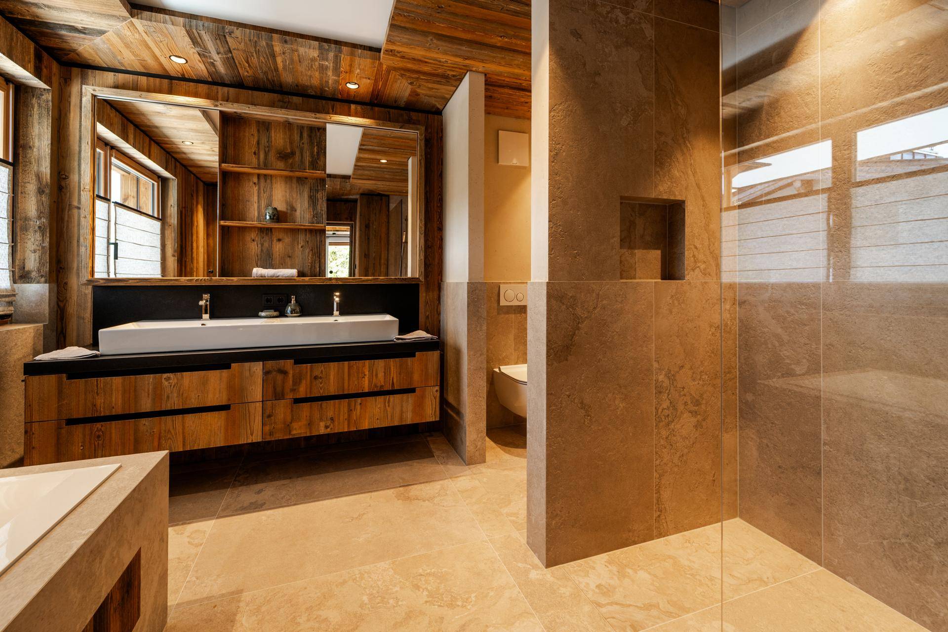 Modernes Badezimmer mit Doppelwaschbecken, Holzunterschrank und großformatigen Fliesen an Wänden und Boden.
