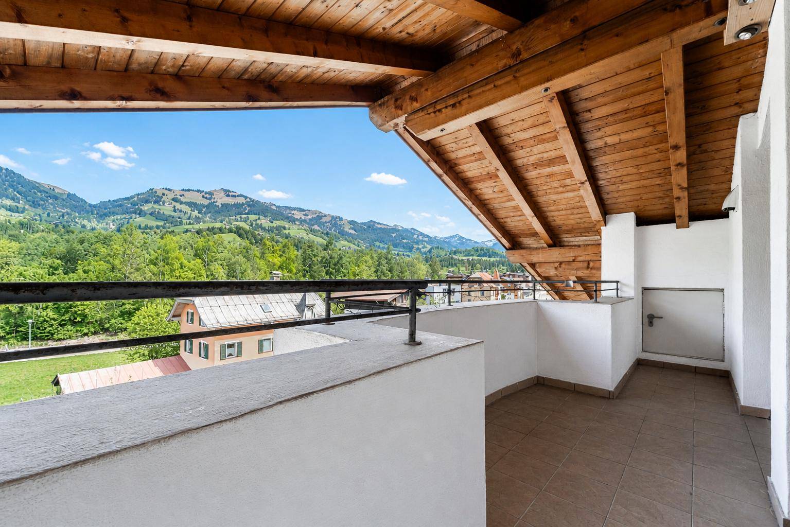 Großer überdachter Balkon mit Holzdach und weitem Blick auf die umliegenden Berge.