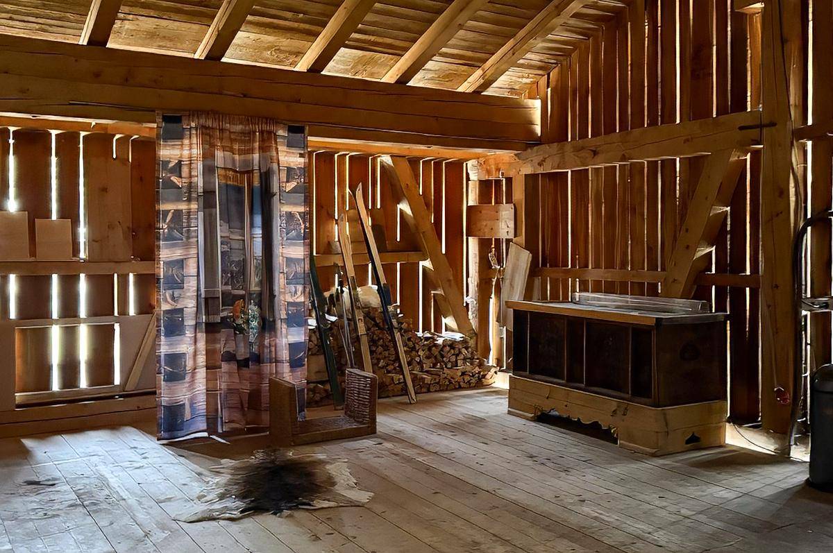 Rustikaler Scheunenraum mit Holzbalken, Holzboden und gestapeltem Brennholz.
