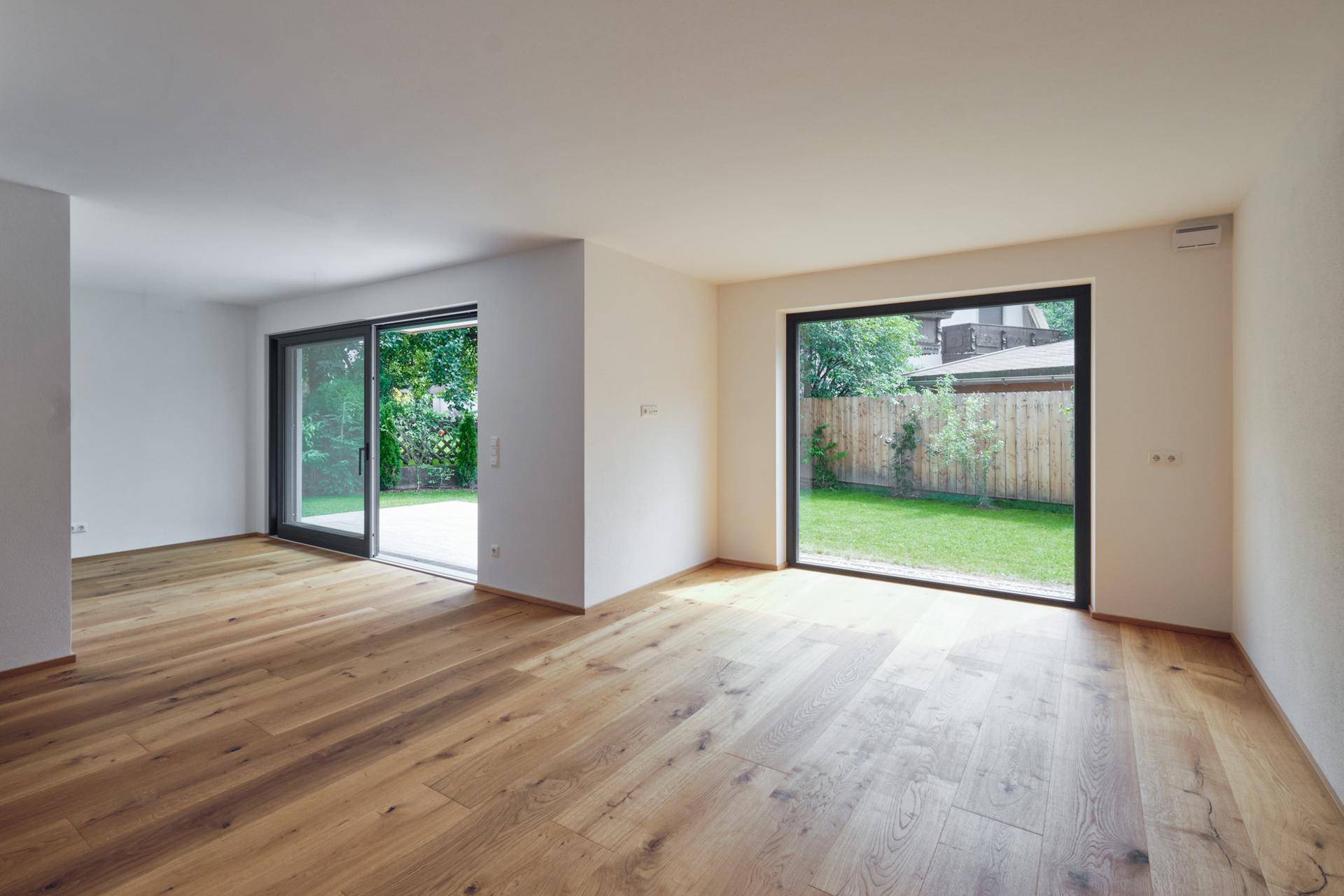 Heller Wohnraum mit Eichenparkett und großen Schiebetüren zum grünen Garten.