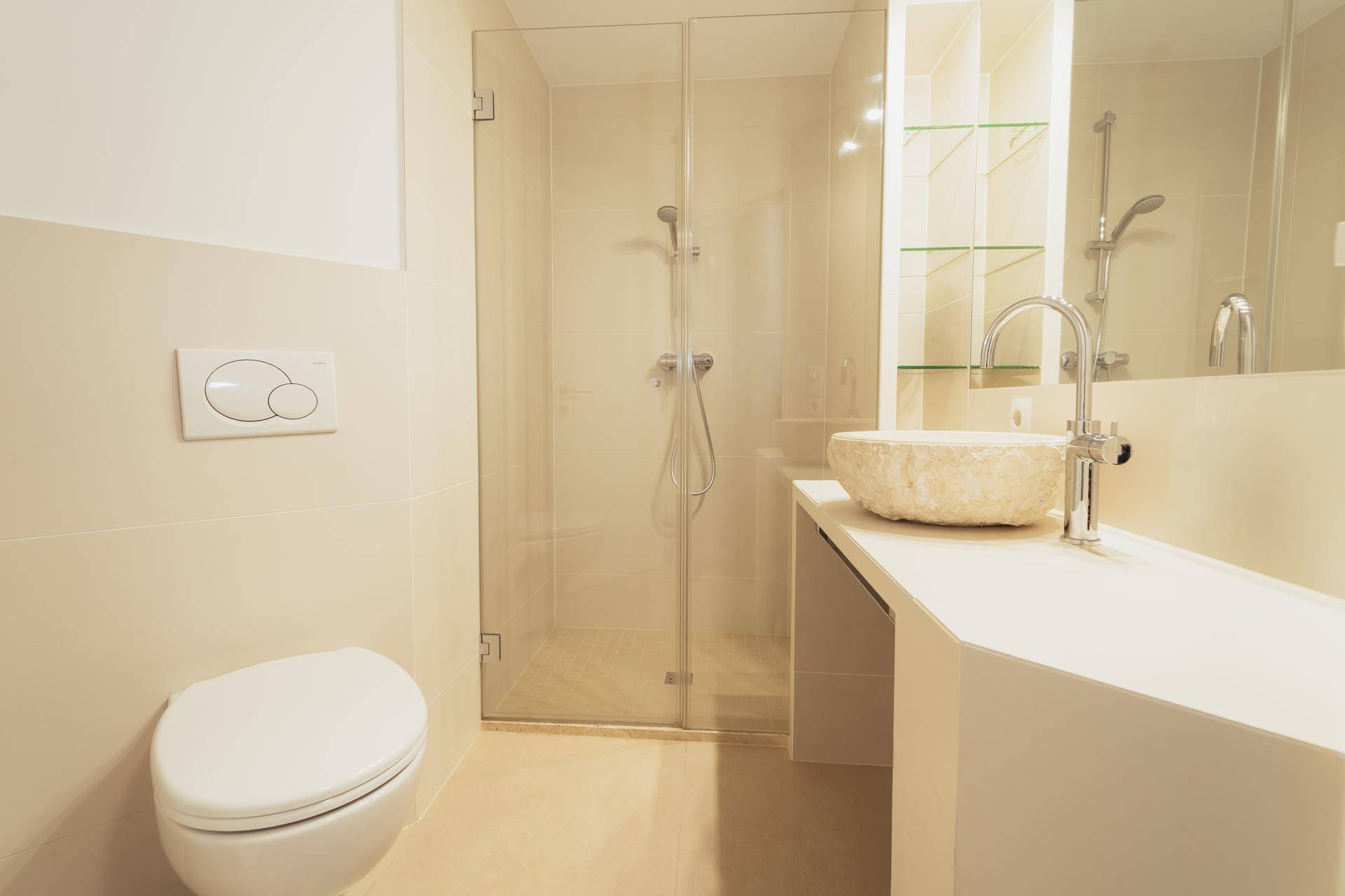 Modernes Badezimmer mit begehbarer Dusche, wandhängendem WC und einem stilvollen Steinwaschbecken.