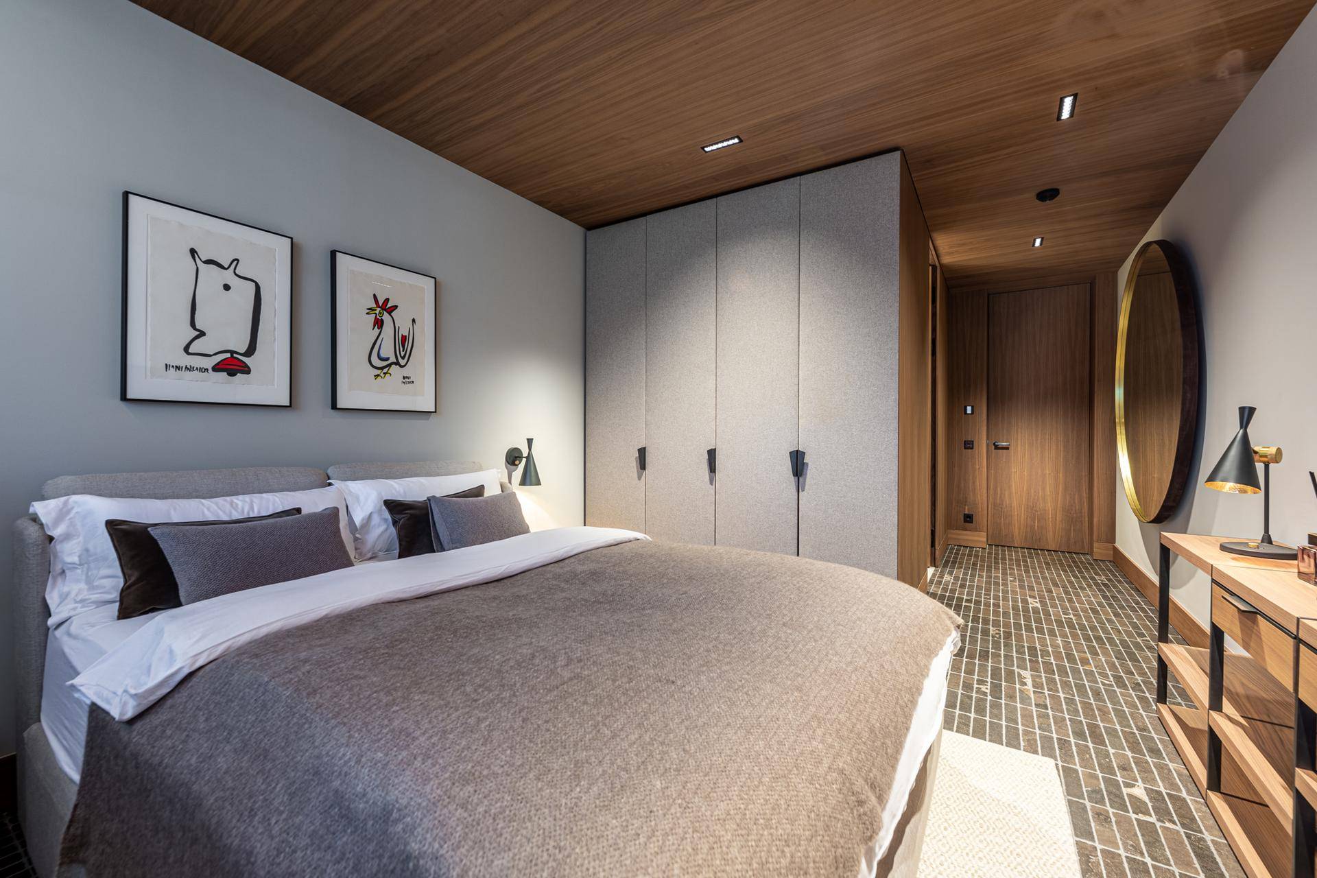 Gemütliches Schlafzimmer mit Holzboden, Einbauschränken und moderner Kunst an den Wänden.