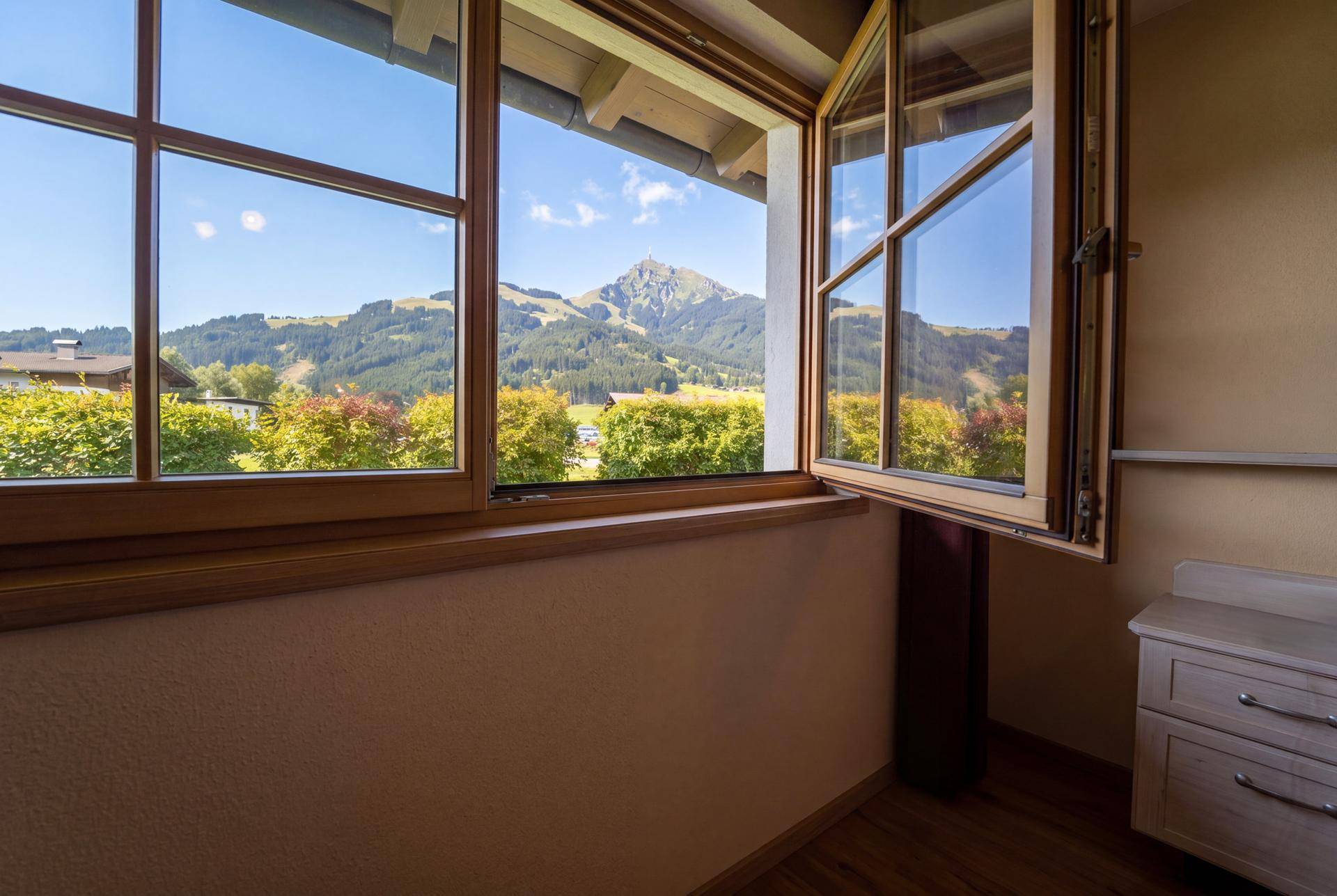Fenster mit Holzrahmen bietet einen malerischen Blick auf die grüne Berglandschaft.