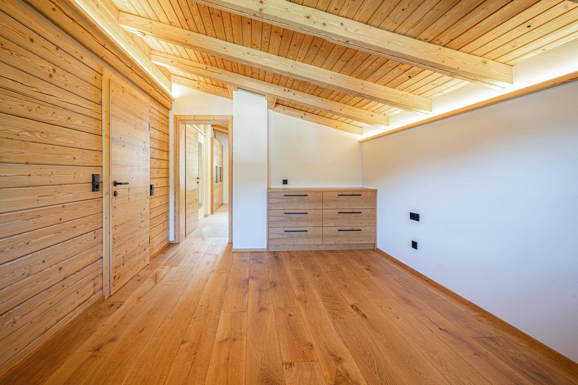 Heller Flur im Dachgeschoss mit Holzbalkendecke, Holzboden und Einbauschränken, führt zu weiteren Räumen.