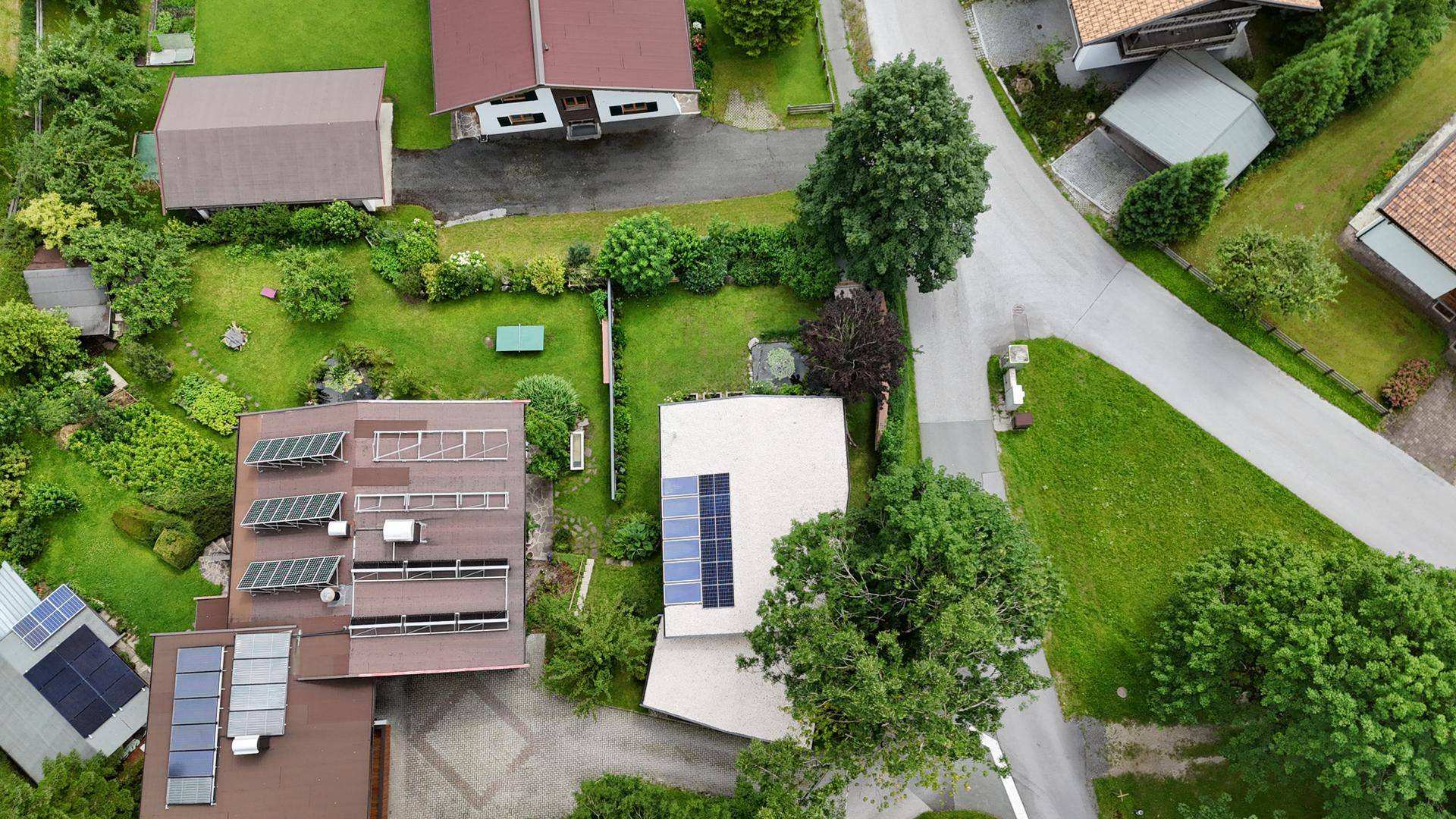 Luftaufnahme einer Wohnsiedlung mit Häusern, Gärten und Photovoltaikanlagen auf den Dächern.