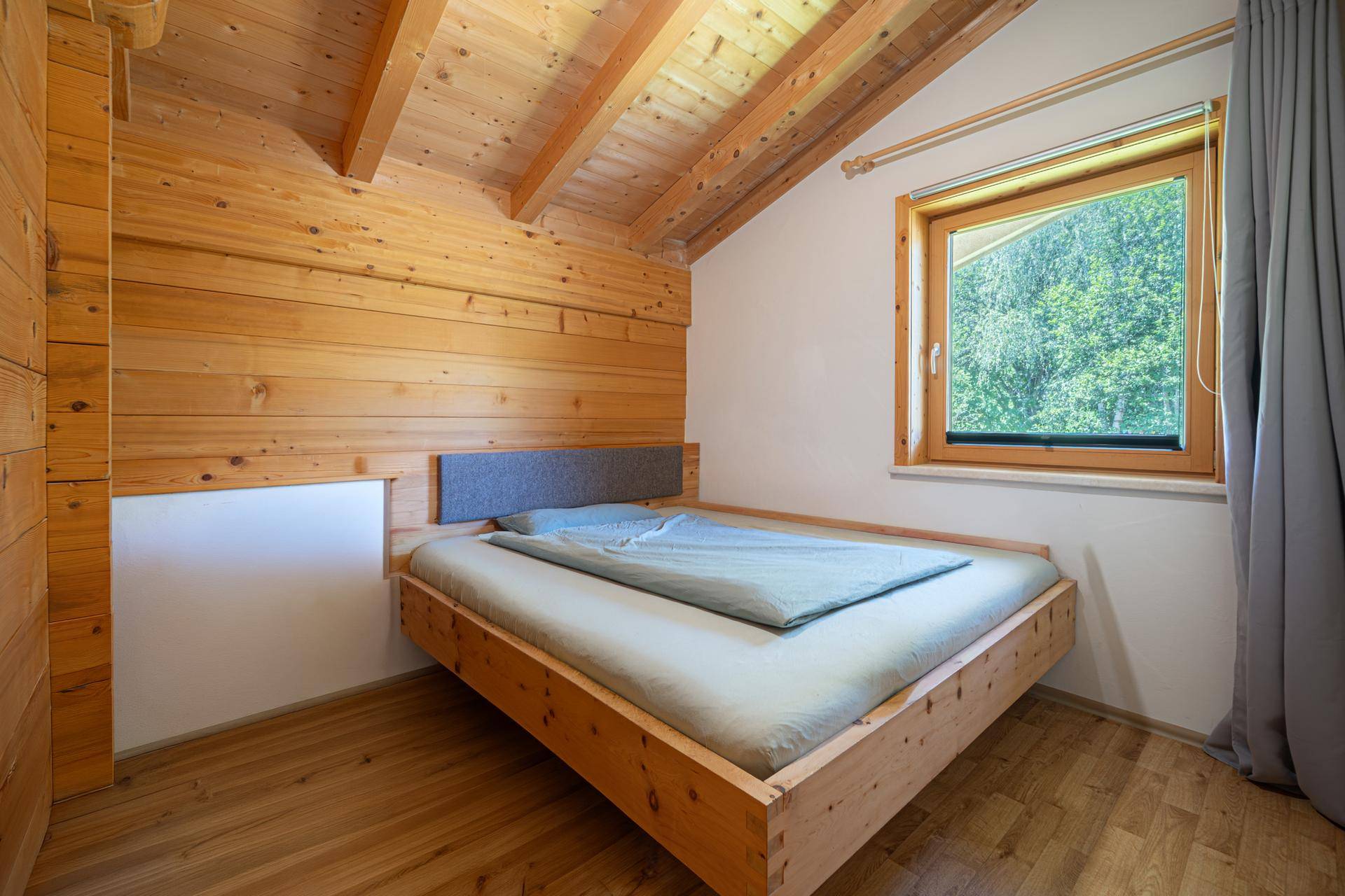 Schlafzimmer mit Holzbett, Holzwänden und schrägen Decken, bietet eine ruhige Atmosphäre.