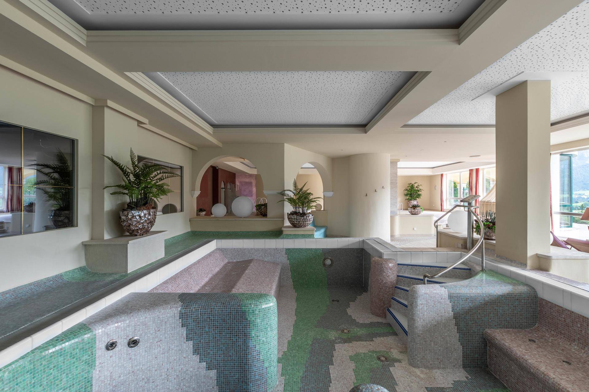 Entspannender Spa-Bereich mit Mosaikfliesenbecken, Pflanzen und indirekter Beleuchtung.
