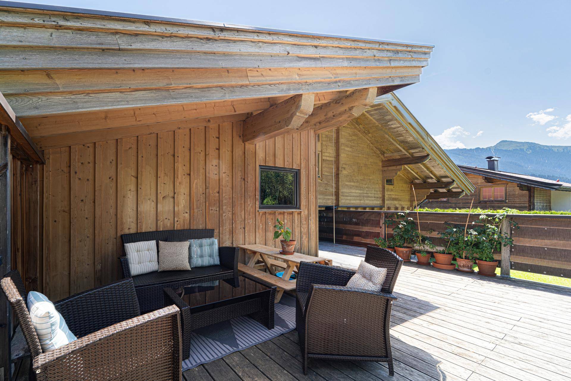 Gemütliche Holzterrasse mit Sitzgelegenheiten und Blick auf die umliegende Berglandschaft.
