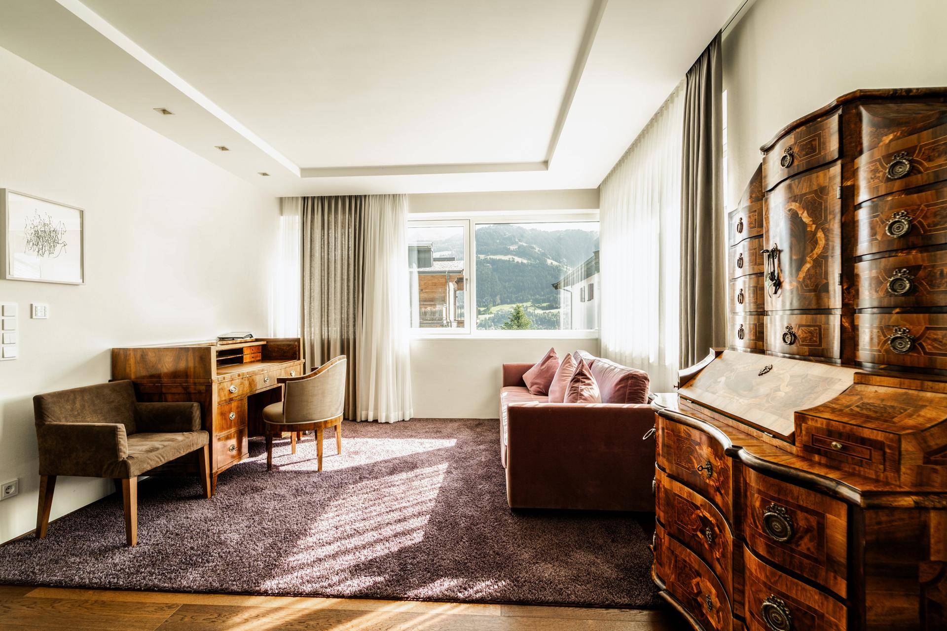 Ruhiges Arbeitszimmer mit antiken Möbeln, Teppichboden und Bergblick durch das Fenster.