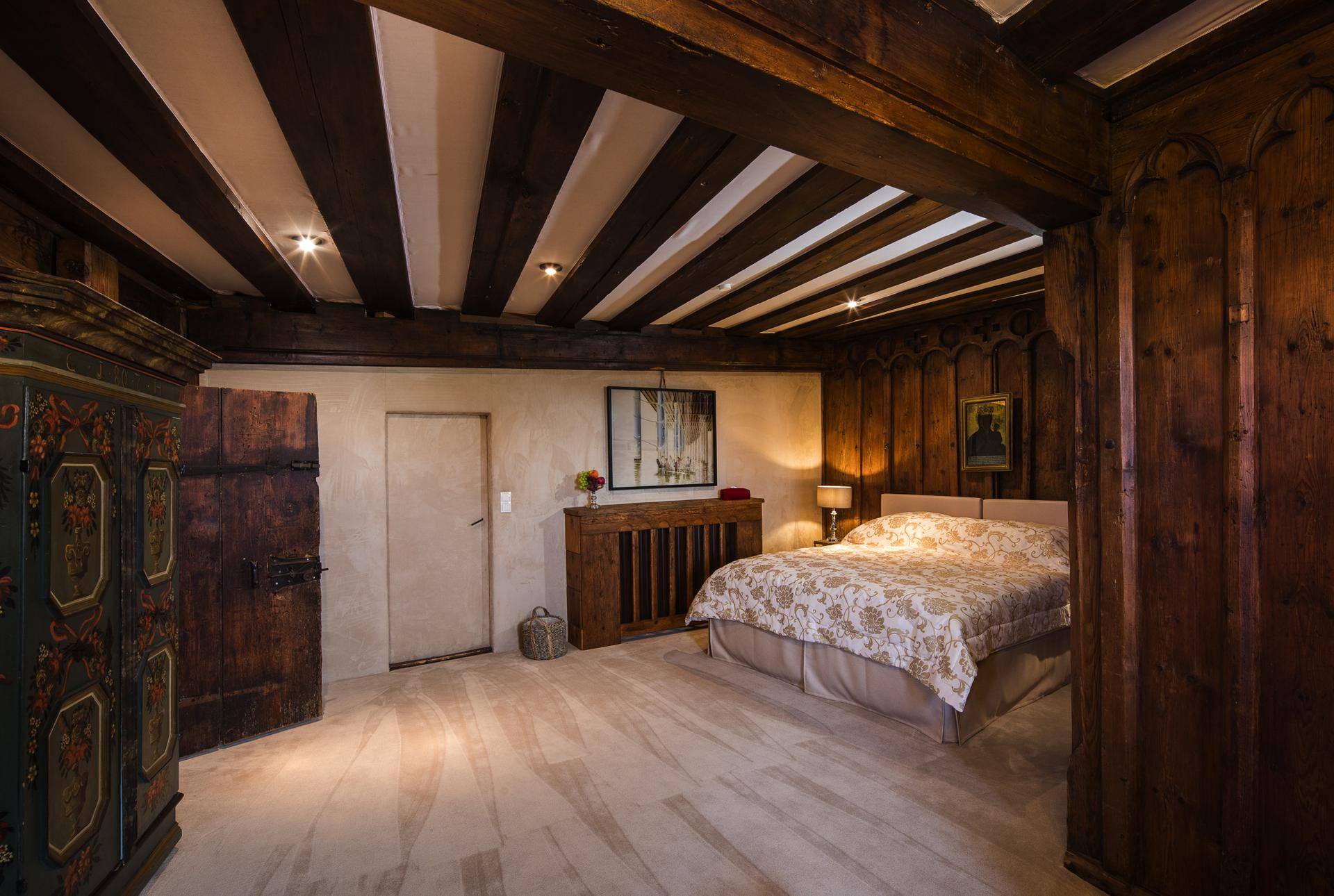 Gemütliches Schlafzimmer mit Holzbalkendecke, traditionellen Möbeln und weichem Teppichboden.