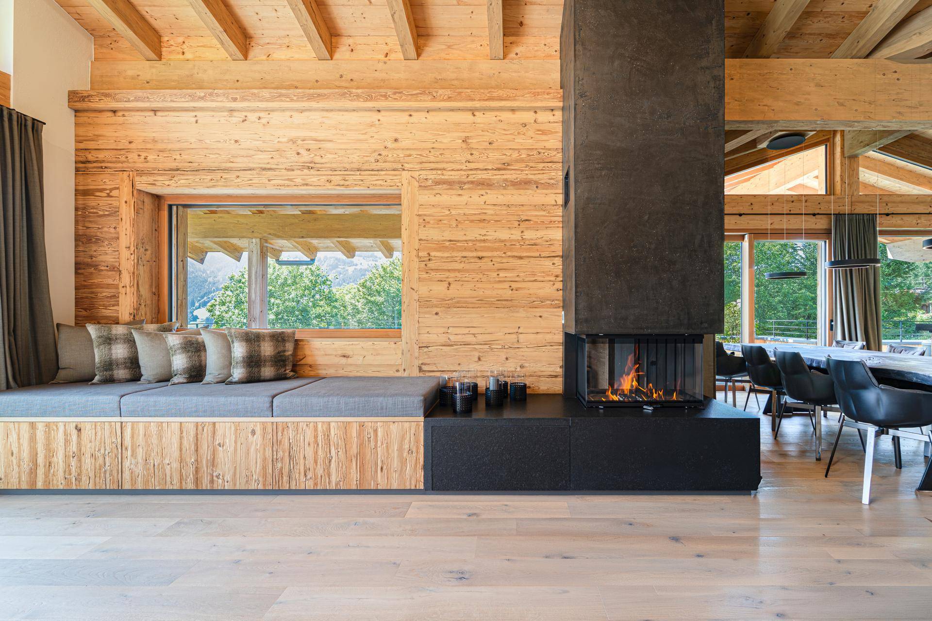 Heller Wohnbereich mit modernem Kamin, Holzwänden und integrierter Sitzbank, offen zum Essbereich.