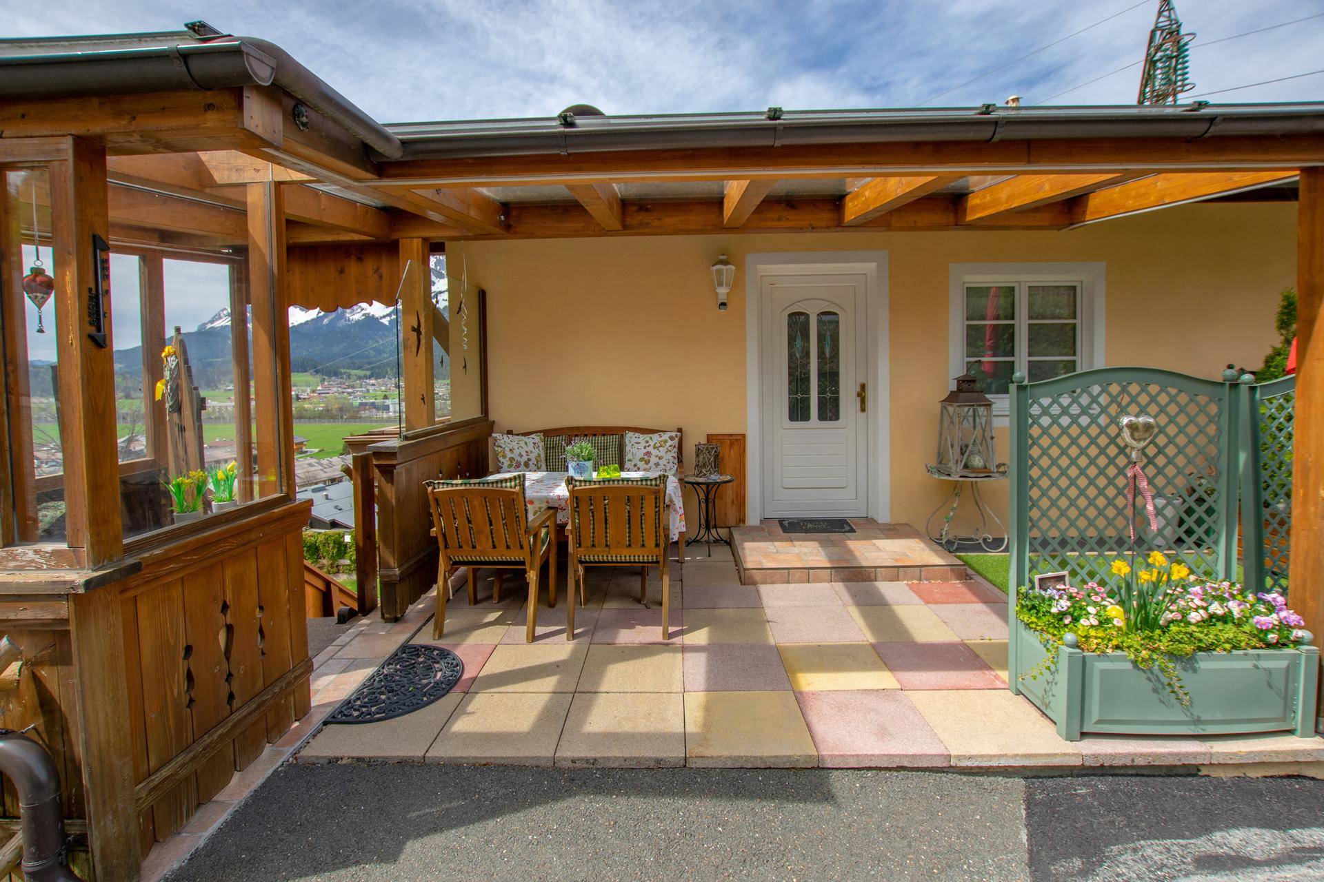 Überdachte Terrasse am Hauseingang mit Sitzgelegenheiten und malerischem Bergblick.