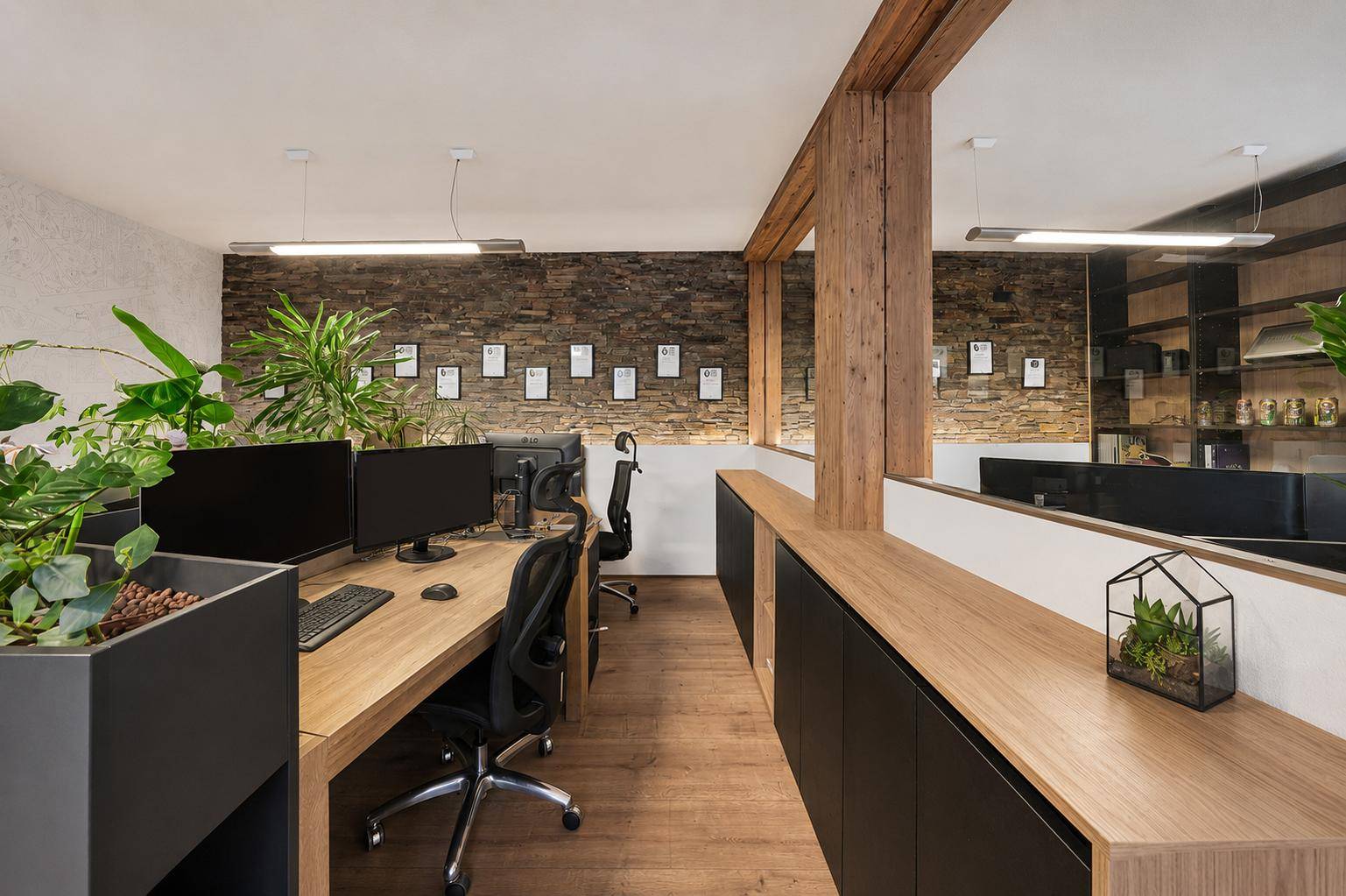 Gut ausgestatteter Arbeitsbereich mit Steinwand, Holztischen und integrierten Pflanzen für eine produktive Umgebung.