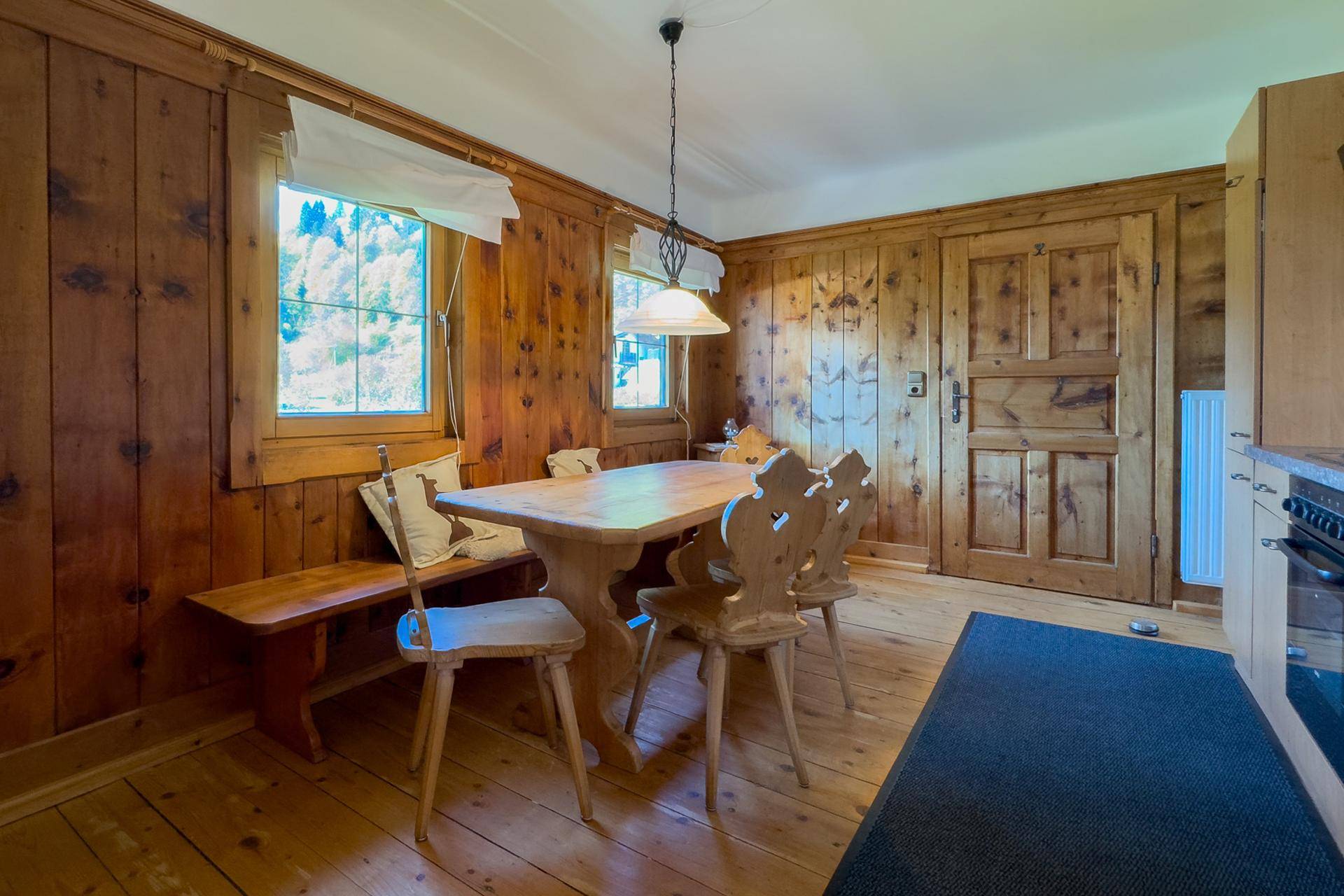 Rustikaler Essbereich mit Holztisch und Stühlen, umgeben von traditioneller Holztäfelung.