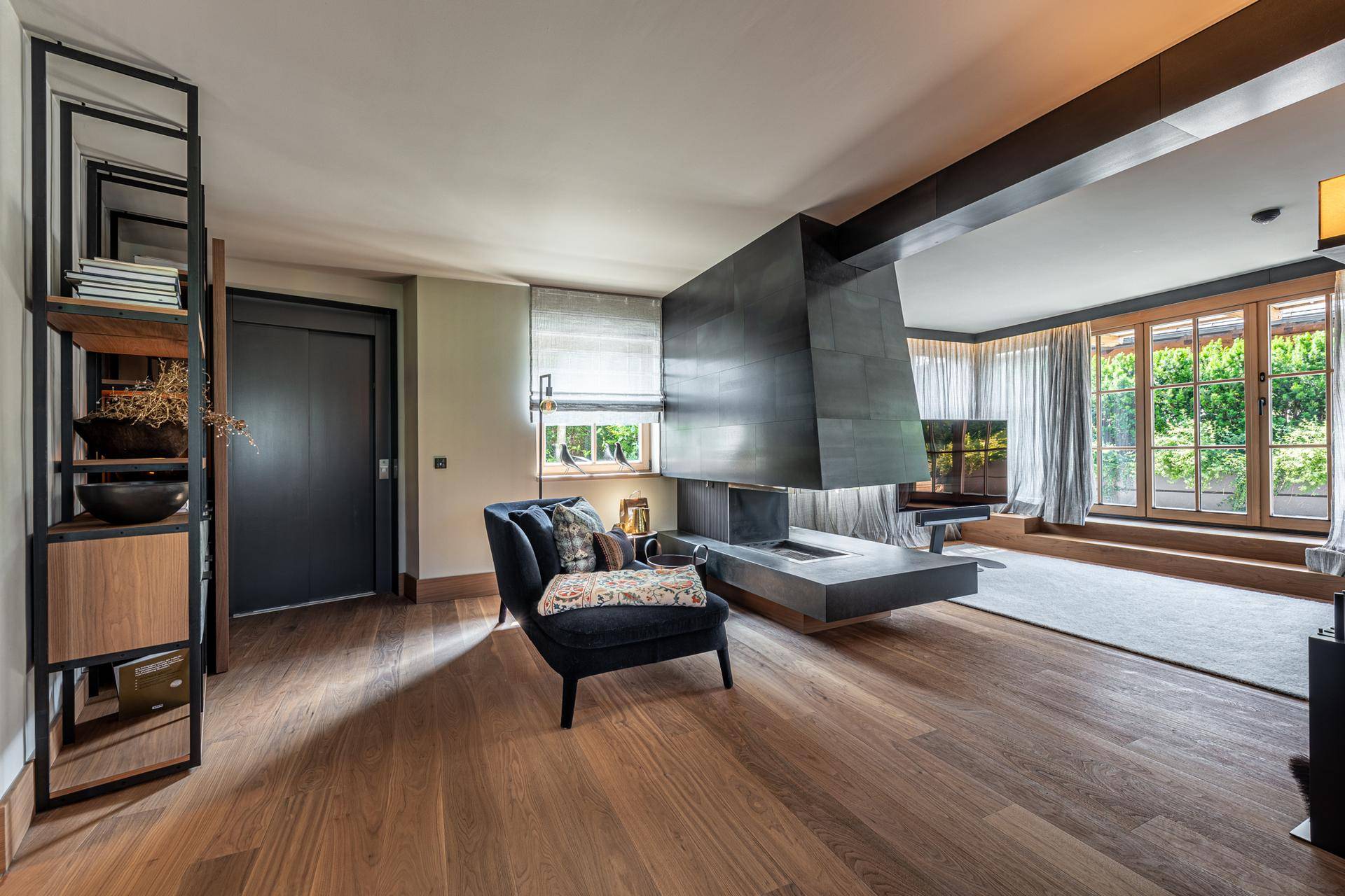 Elegantes Wohnzimmer mit Holzboden, modernem Kamin und großen Fenstern, die viel Licht hereinlassen.