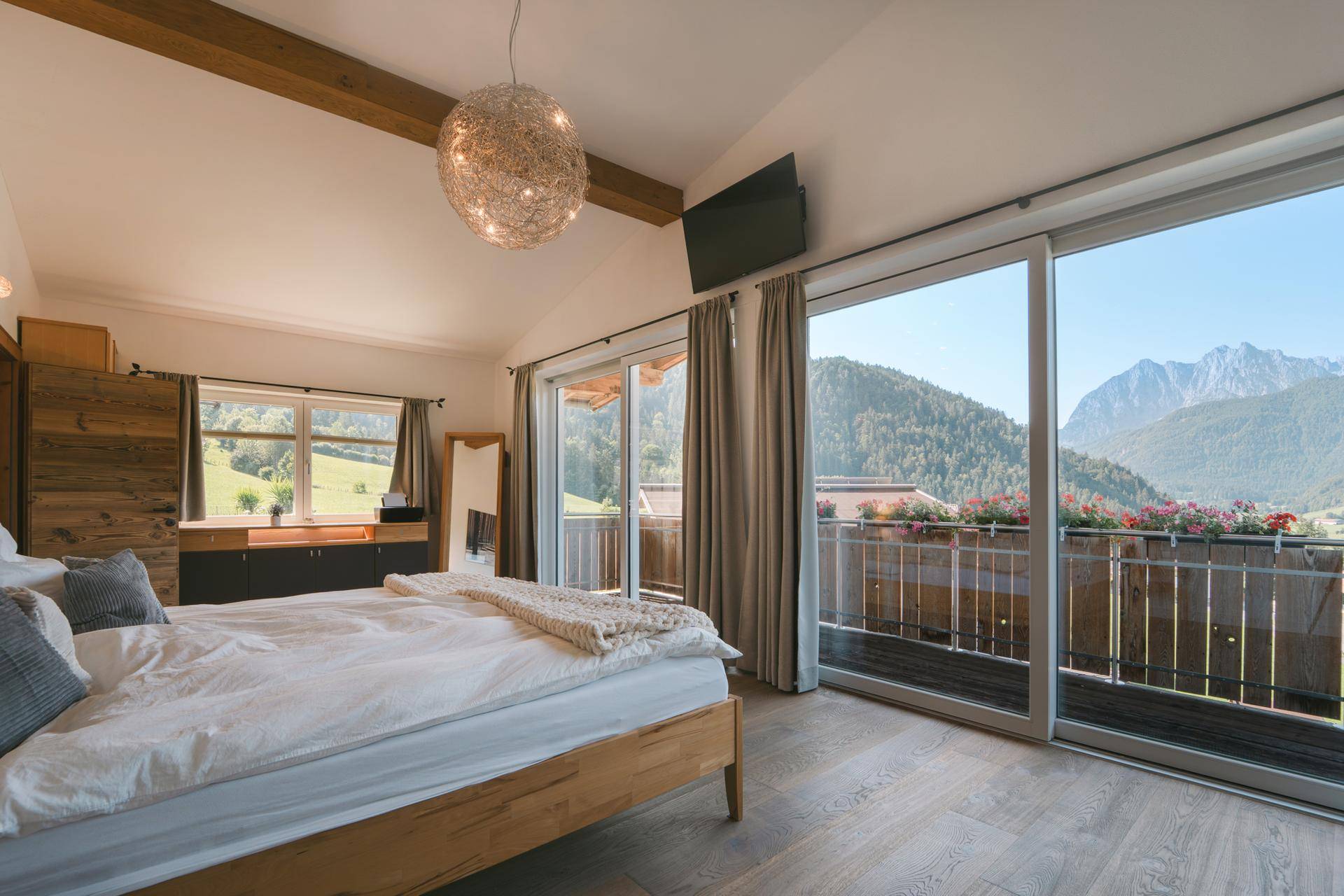 Helles Schlafzimmer mit Balkonzugang, Holzboden und herrlichem Bergblick.