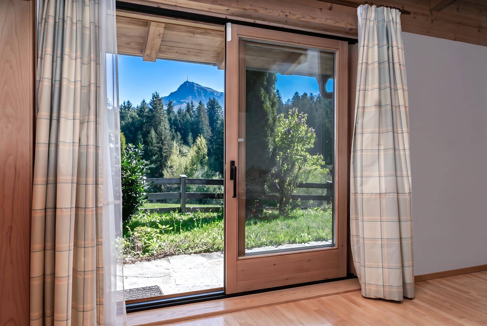 Große Glasschiebetür bietet Zugang zum Garten und einen weiten Blick auf die umliegende Berglandschaft.