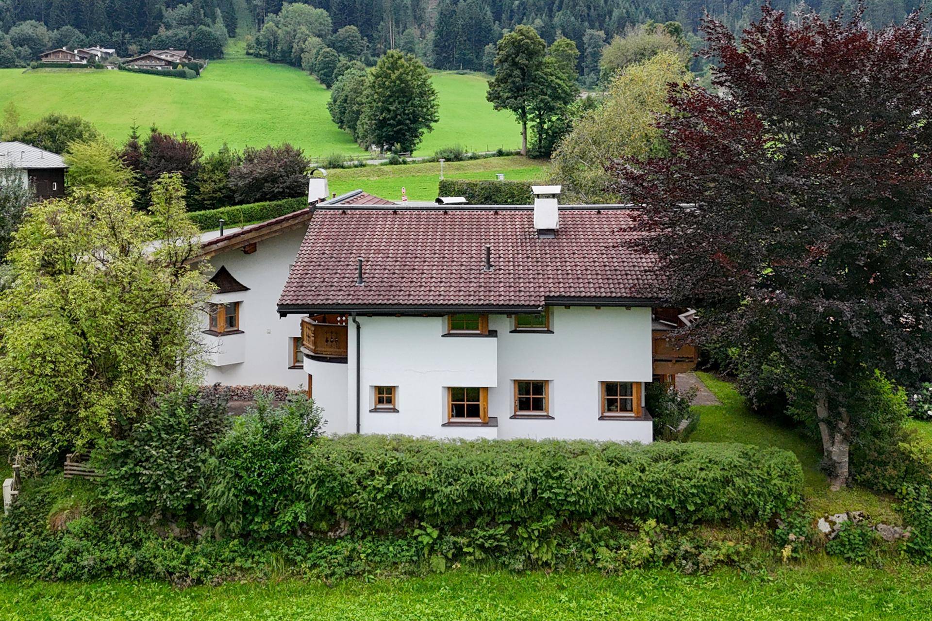 Seitenansicht des Hauses, umgeben von dichten Hecken und üppiger grüner Landschaft.