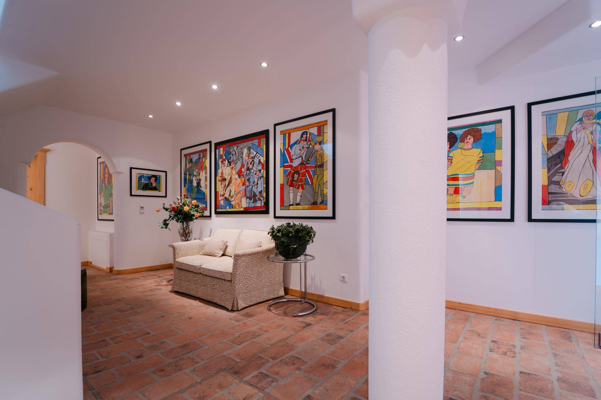 Heller Flur mit Terrakotta-Fliesenboden und modernen Kunstwerken, führt zu weiteren Wohnbereichen.