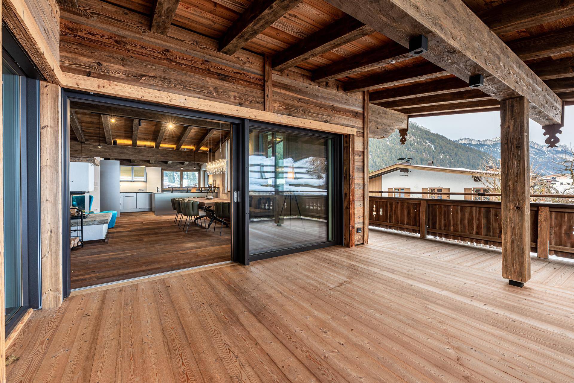 Geräumige Holzterrasse mit Blick auf die verschneite Landschaft und Zugang zum Wohnbereich.