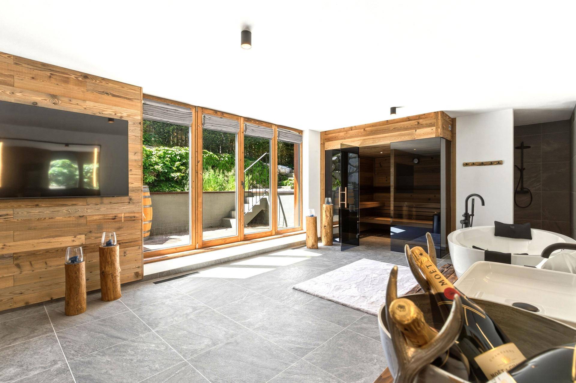 Exklusiver Wellnessbereich mit Sauna, freistehender Badewanne und Zugang zum Außenbereich.