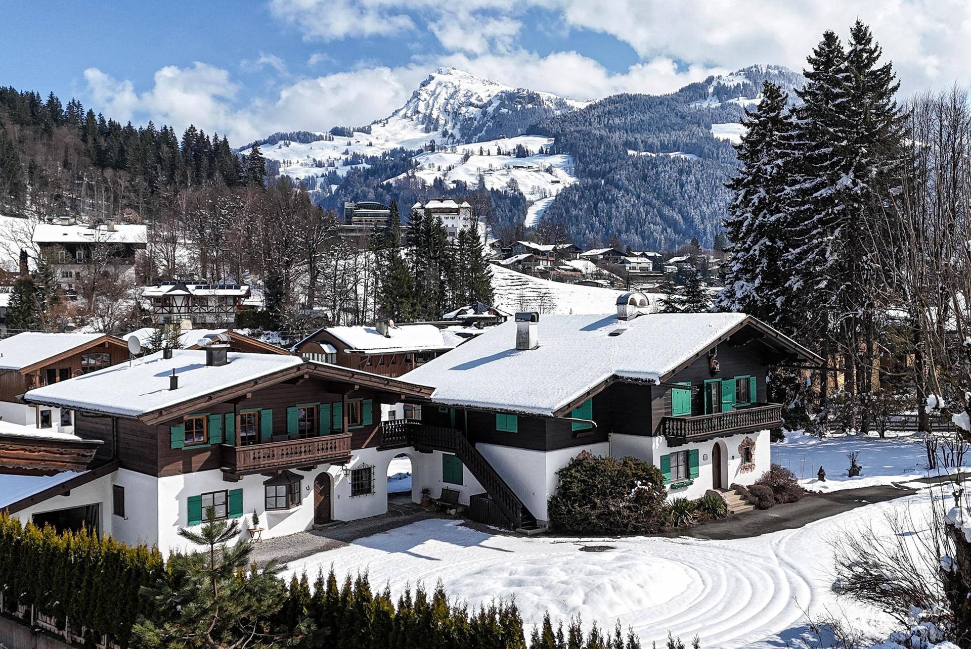 Traditionelles Haus im Winter mit schneebedecktem Dach und Bergblick.