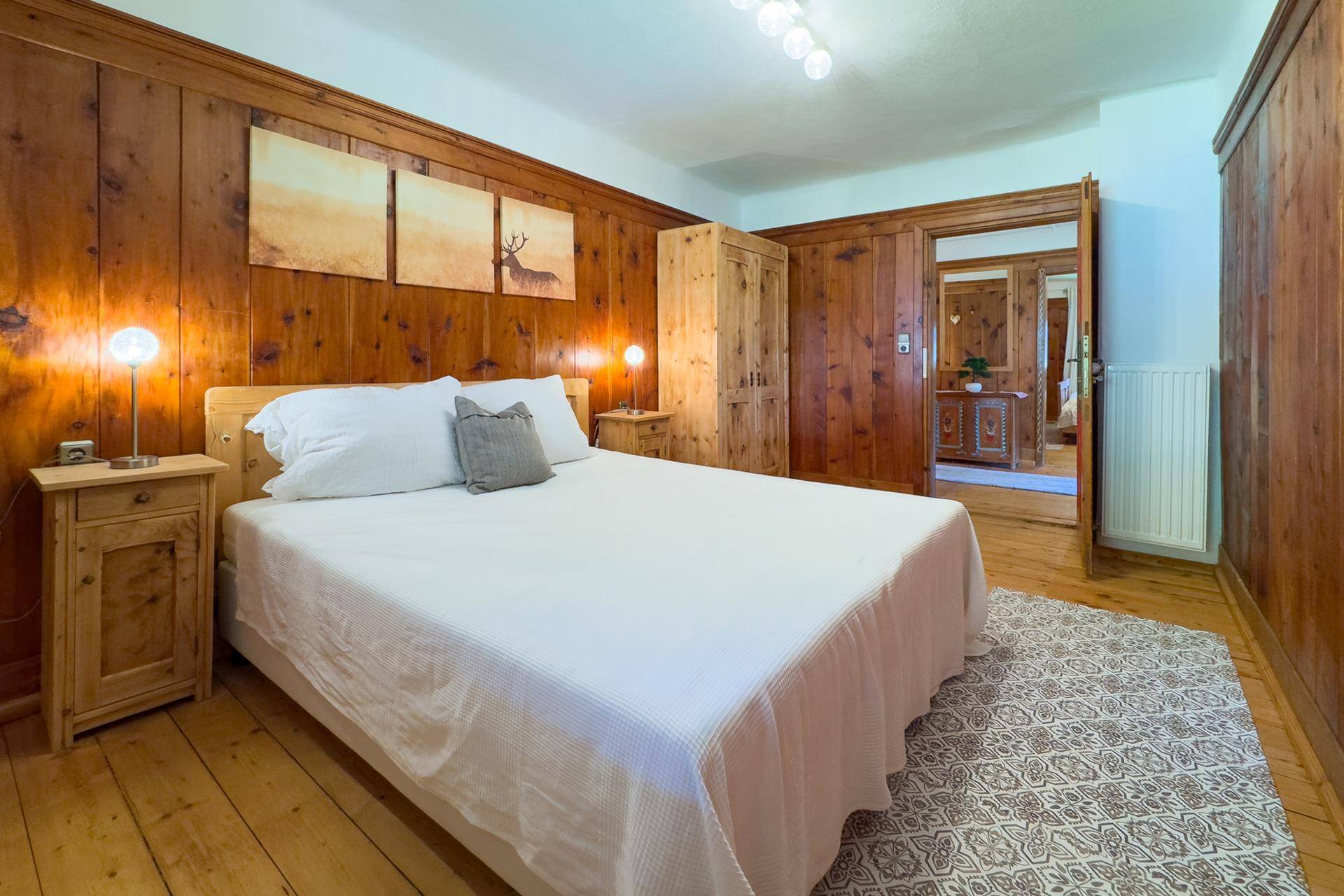 Schlafzimmer im Landhausstil mit Doppelbett, Holztäfelung und rustikalen Möbeln.