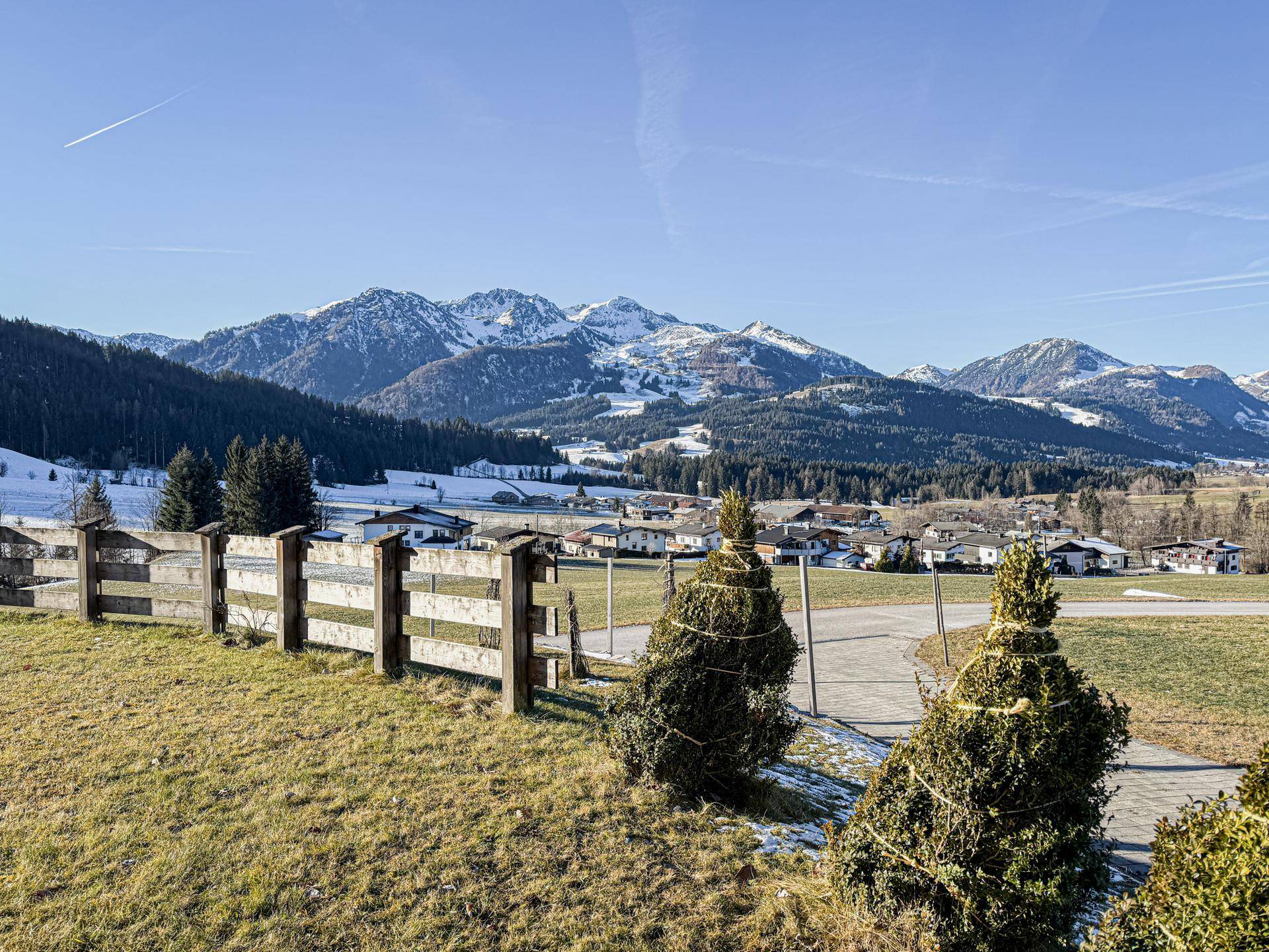 Weitläufiger Blick auf die verschneite Berglandschaft und ein Dorf im Tal.