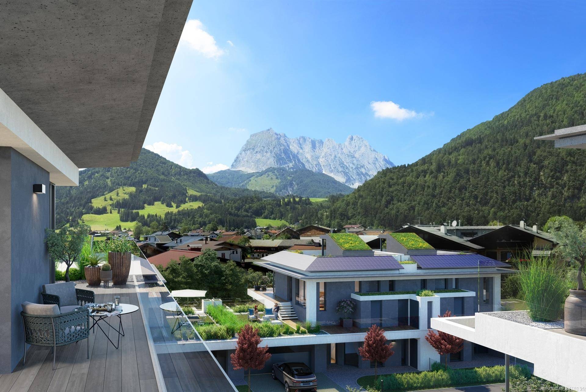 Balkon mit Glasbrüstung und Sitzgelegenheiten bietet einen weiten Blick auf die Berge und das Dorf.