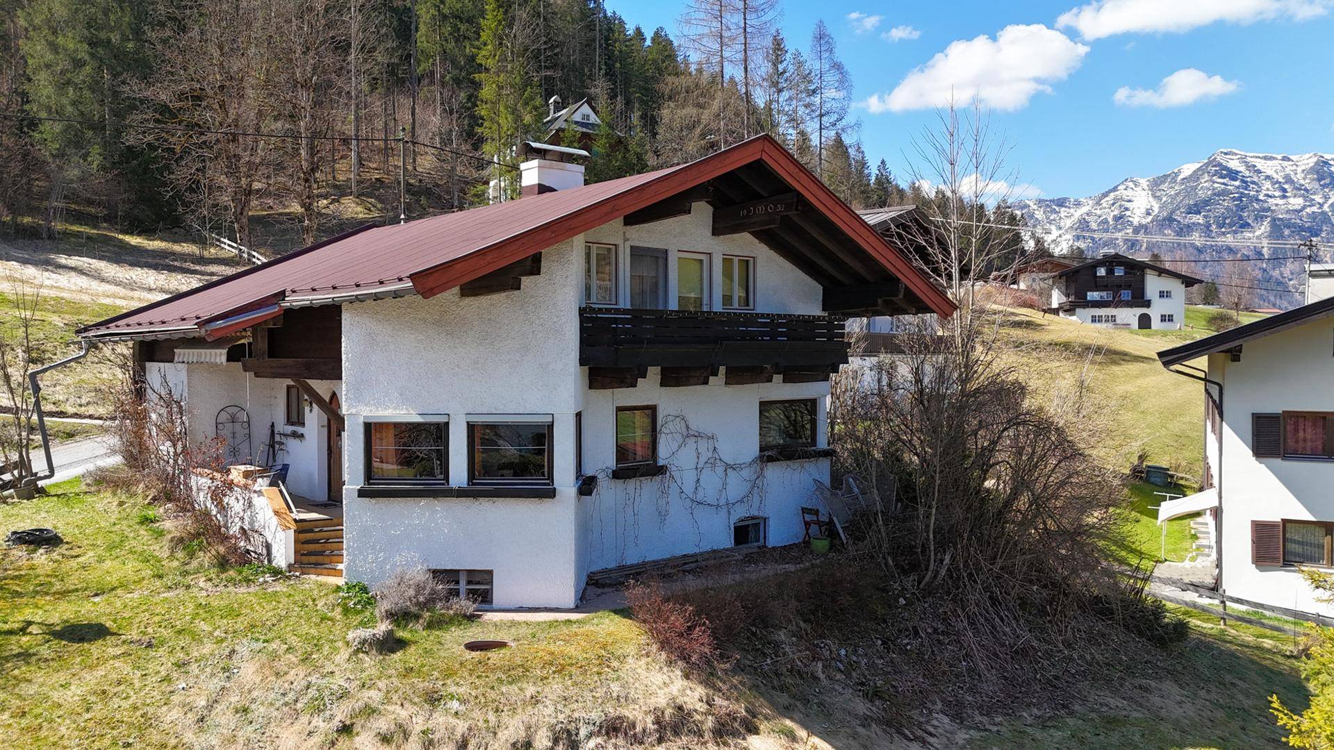 Nahaufnahme des Hauses mit traditionellem Satteldach, Holzbalkonen und weißer Fassade.