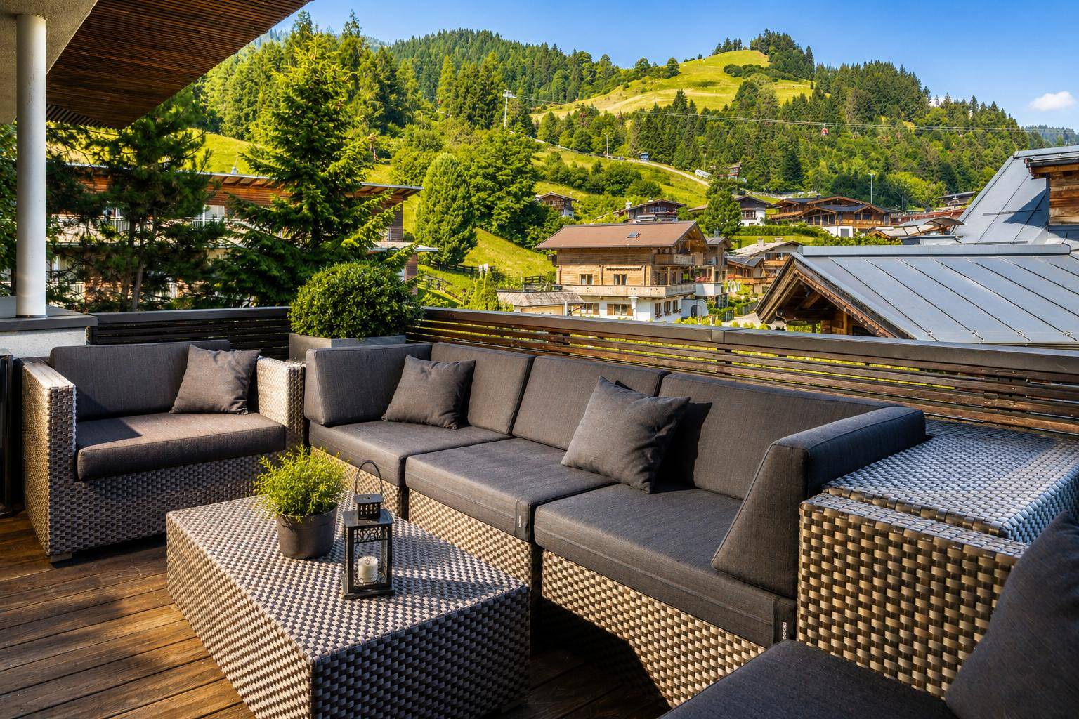 Große Terrasse mit bequemen Loungemöbeln und Panoramablick auf die umliegende Berglandschaft.