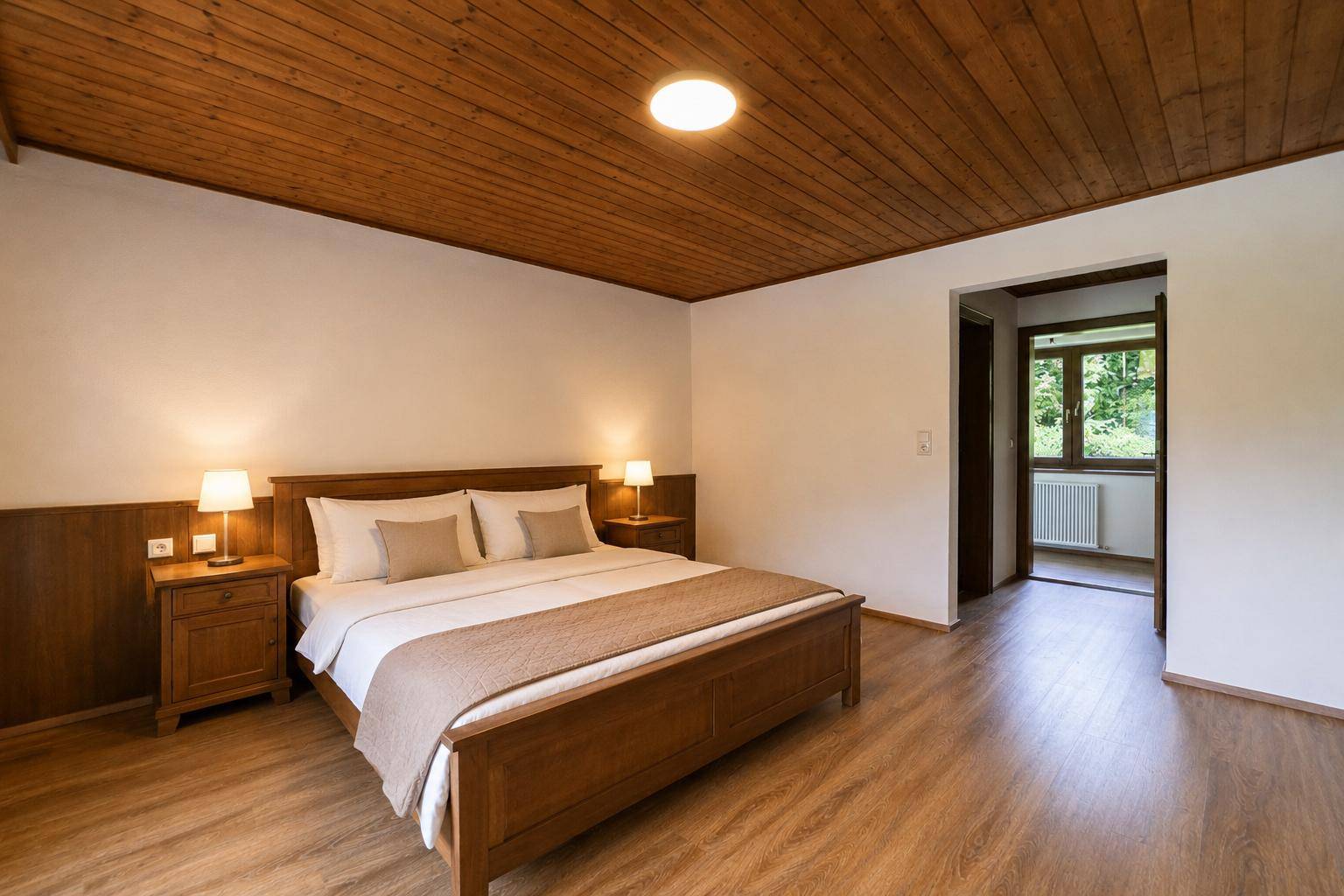 Schlafzimmer mit Doppelbett, Holzdecke und Laminatboden in warmer Atmosphäre.