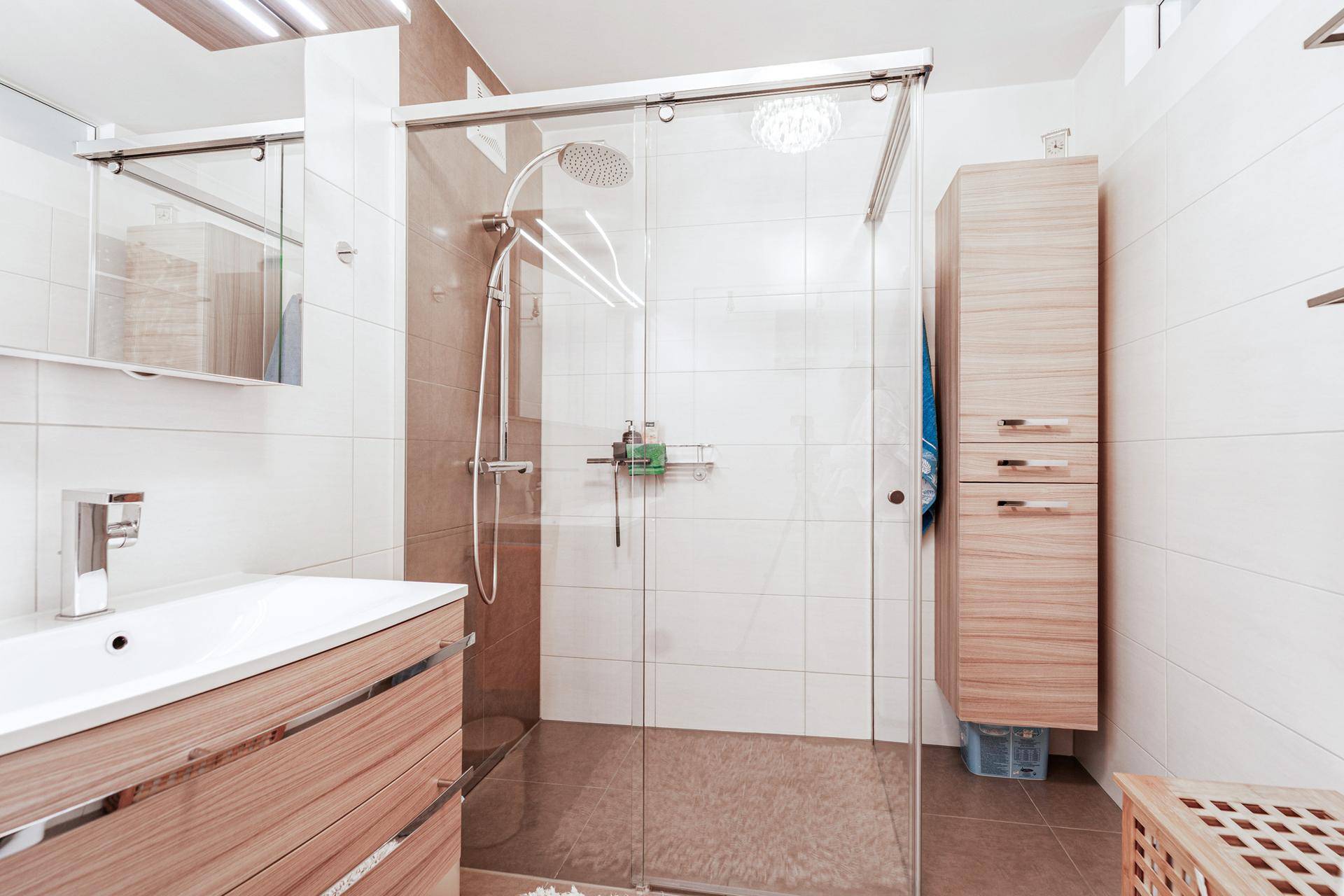 Modernes Badezimmer mit begehbarer Dusche, Holzwaschtisch und weißen Fliesen.